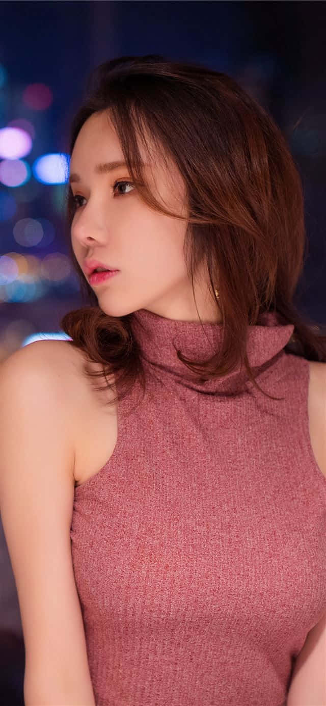 Cute Girly Girl 桌布 壁紙 — 一位身穿粉紅色紋理上衣的女性，在模糊的城市夜景背景下，凝視著閃爍的散景燈光，若有所思。
