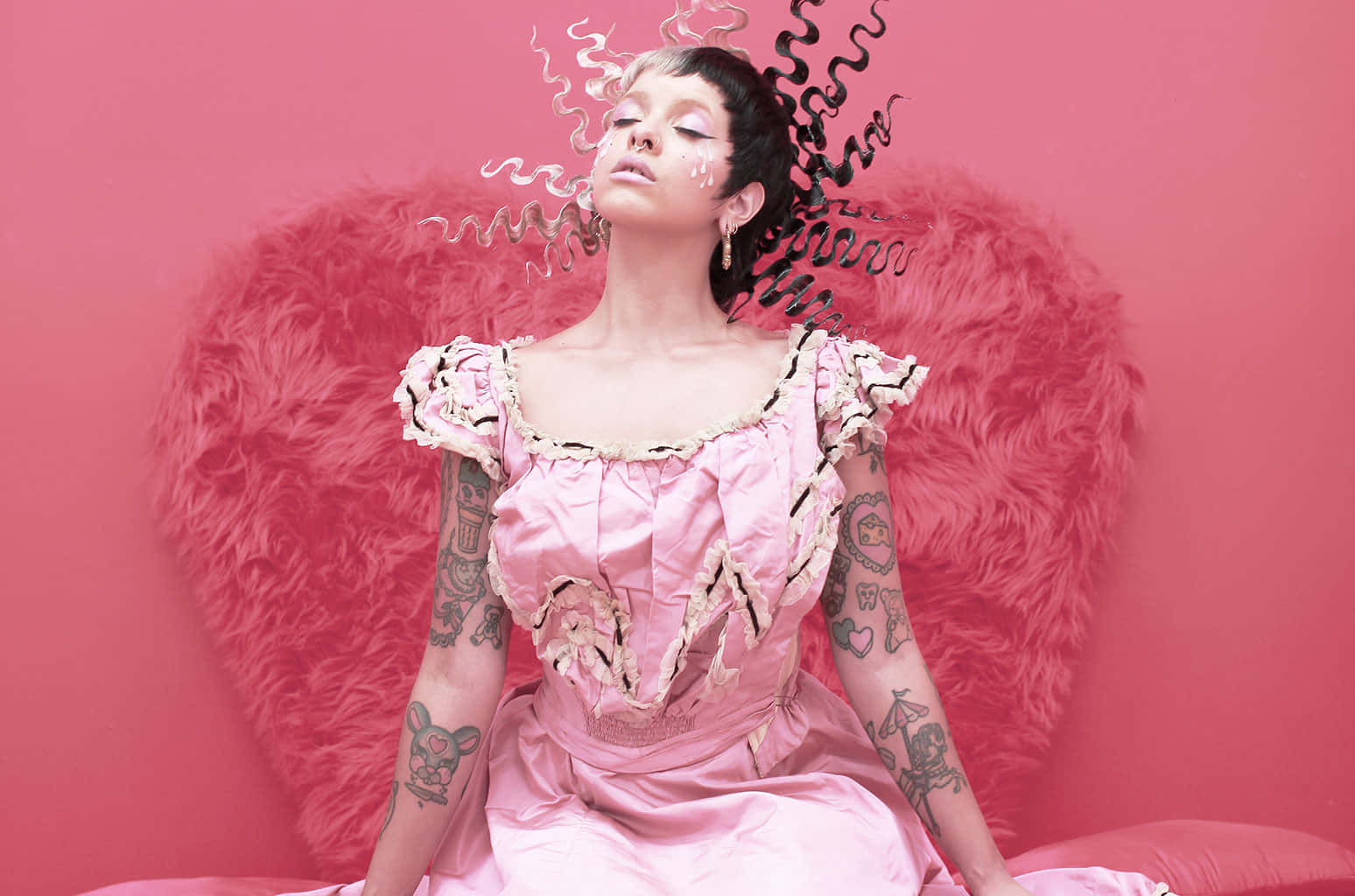 Melanie Martinez 桌布 壁紙 — 一位身穿粉紅色緞面連衣裙、帶有刺青的女性，坐在一個蓬鬆的粉紅色心形背景前，背景中有旋轉的黑白煙霧。