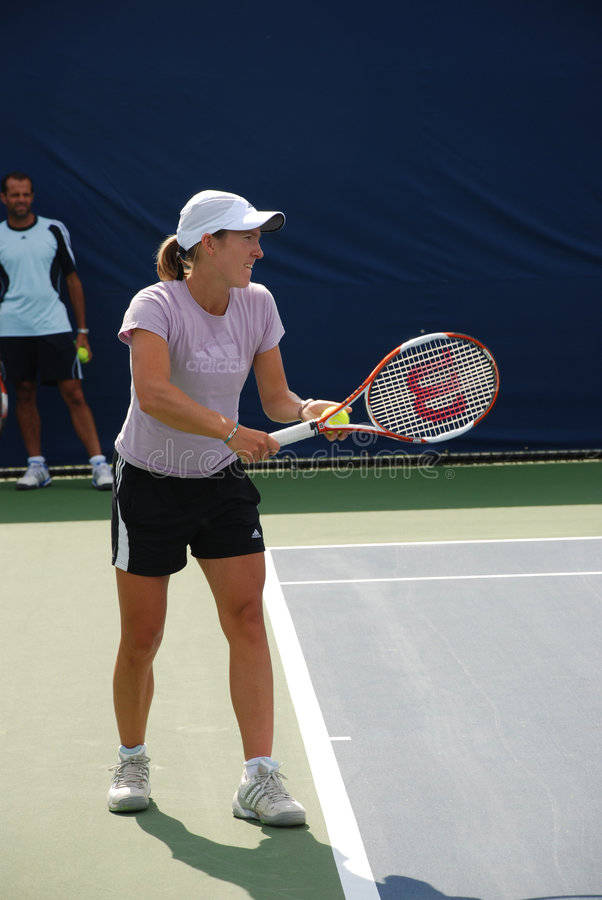 Tennis 桌布 壁紙 — 一位身穿粉紅色襯衫和白色帽子的女網球運動員在陽光明媚的戶外球場上準備正手擊球。