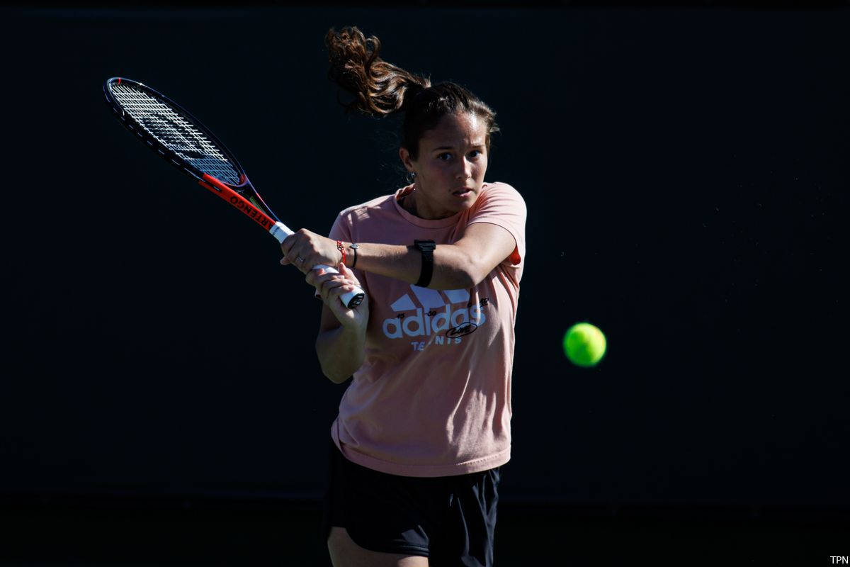 Athletic 桌布 壁紙 — 一位身穿粉紅色襯衫的女網球運動員在深色背景下揮拍擊打一個亮綠色的球。