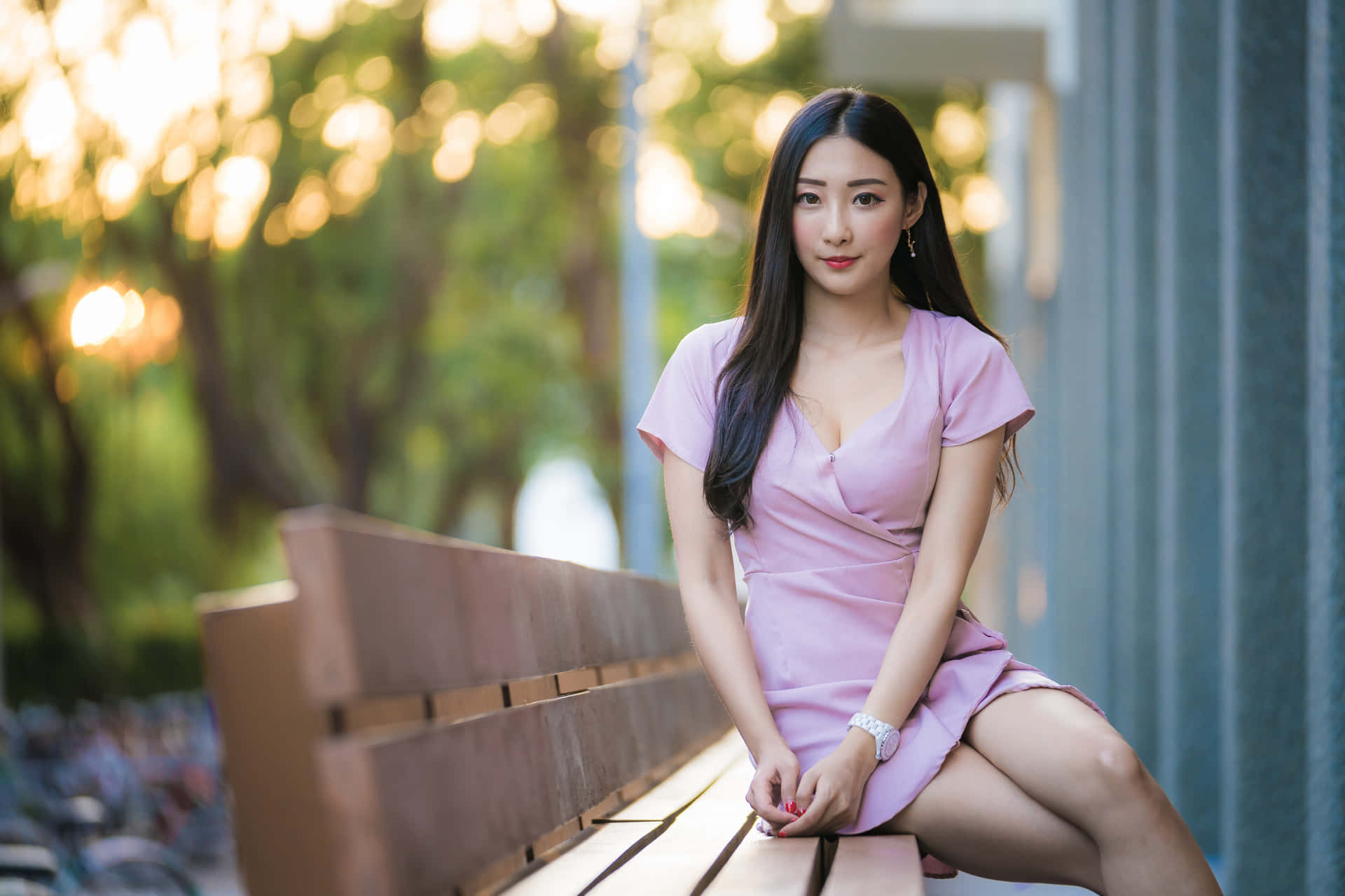 身穿粉紅色連衣裙的女性坐在陽光普照的公園木長椅上 — 漂亮的動圖 壁紙