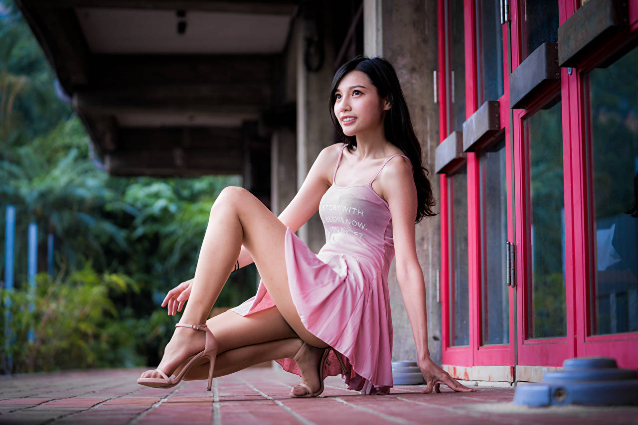 Woman 桌布 壁紙 — 一位身穿粉紅色連衣裙的女性優雅地坐在瓷磚門廊上，旁邊是紅色邊框的窗戶，身後是茂密的綠色植物。