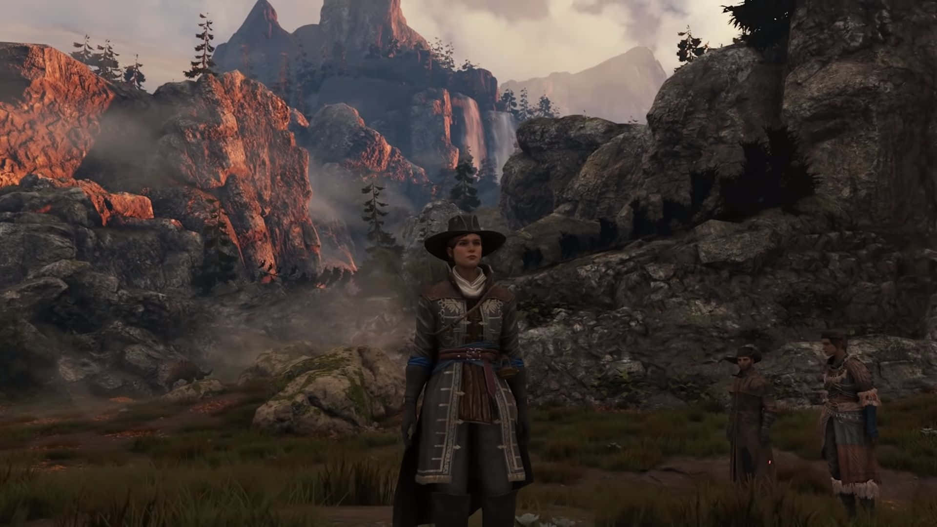 Greedfall 桌布 壁紙 — 一位身穿粗獷服裝的孤獨冒險家站在霧氣繚繞的山脈前，沐浴在金色的日落光芒中，背後有瀑布傾瀉而下。