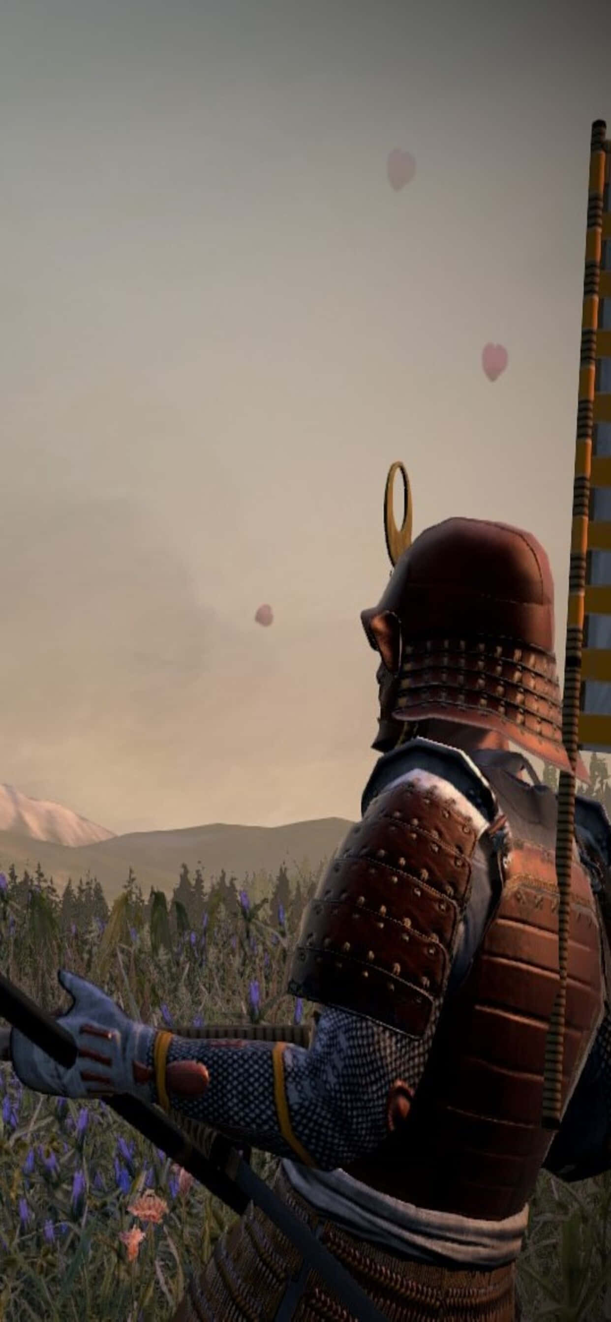 iPhone Xs Max Total War Shogun 2 桌布 壁紙 — 一位身穿精細盔甲的武士站在紫色花田中，凝視著漂浮的粉紅色愛心，背景是朦朧的山巒。