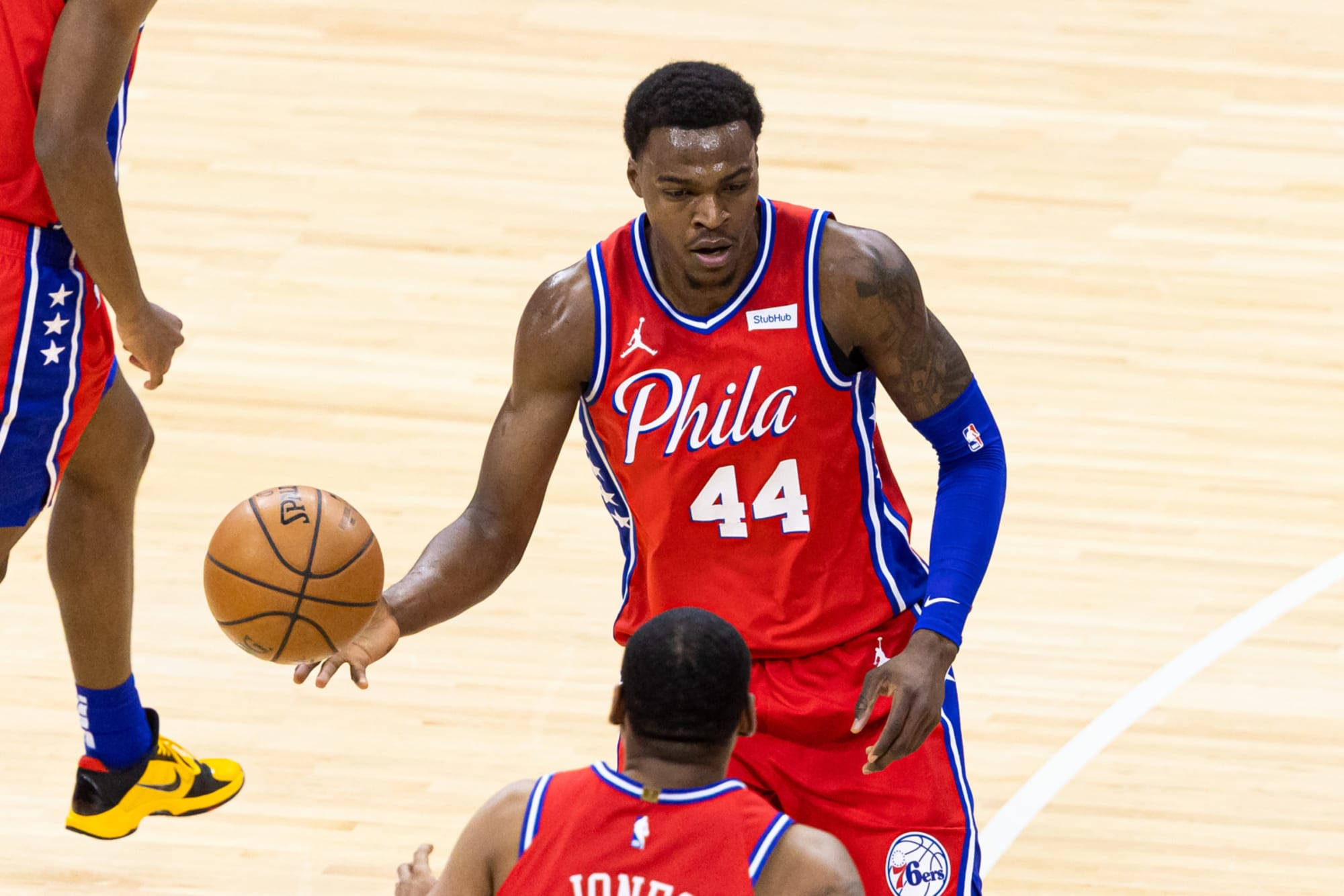 76ers 桌布 壁紙 — 一位身穿紅色44號球衣的費城76人籃球運動員在拋光木地板上進行激烈比賽時運球。