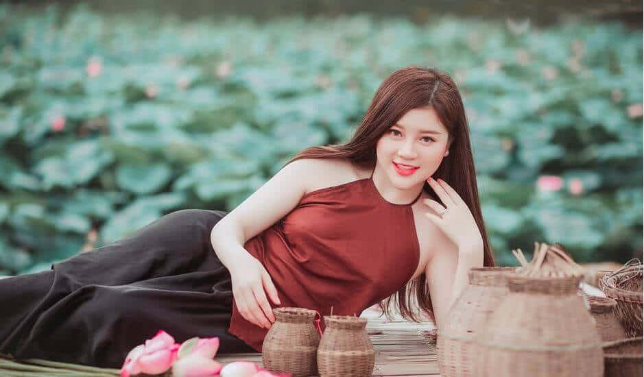 美女 桌布 壁紙 — 一位身穿紅色上衣的女性，在寧靜的蓮花池中的竹筏上，優雅地躺在編織籃子旁邊。