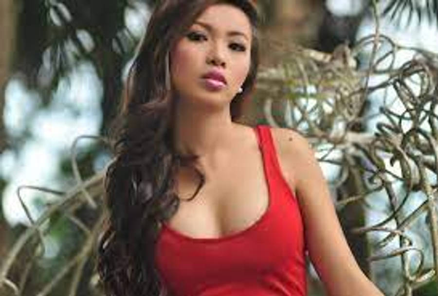 Woman 桌布 壁紙 — 一位身穿紅色上衣的女性在茂密的綠色樹葉中擺姿勢，光線柔和自然。