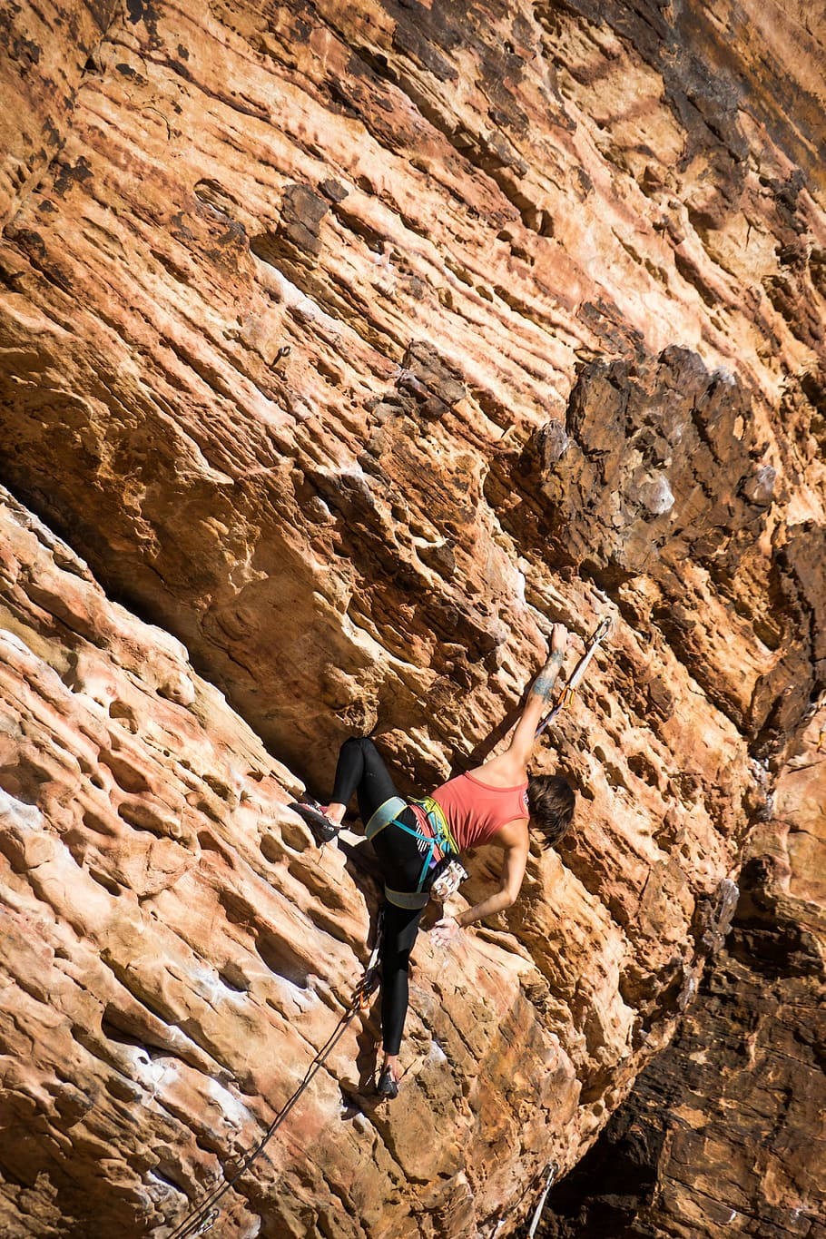 Climbing 桌布 壁紙 — 一位身穿紅色上衣的攀岩者在明亮的陽光下攀登陡峭的橙色紋理岩壁。