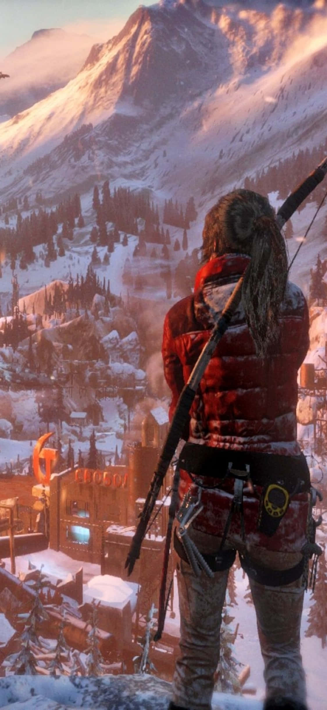 iPhone X Rise Of The Tomb Raider 桌布 壁紙 — 一位身穿紅色外套的孤獨冒險家站在白雪覆蓋的山峰上，俯瞰著金色夕陽下冰封的山村。