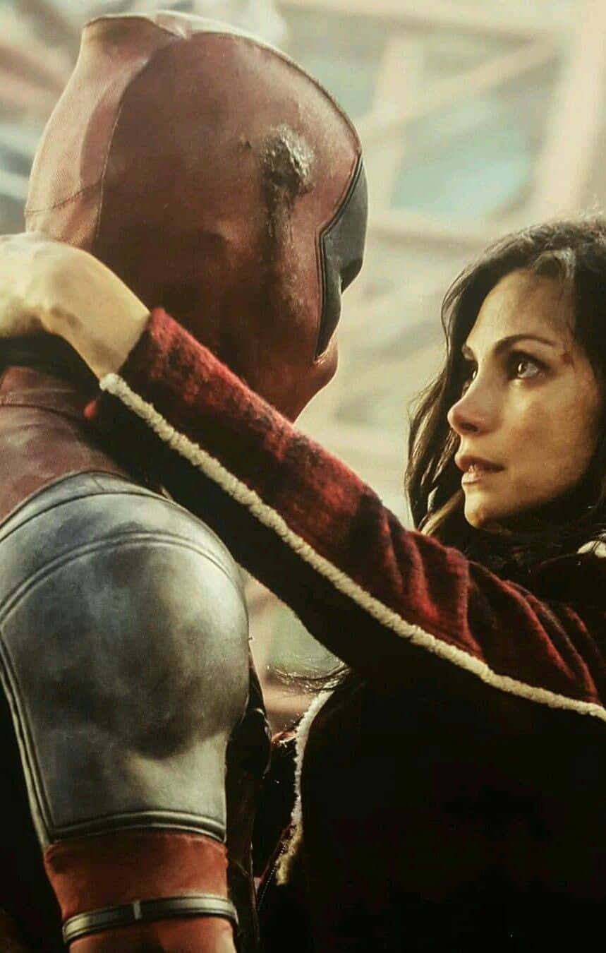 Deadpool And Vanessa 桌布 壁紙 — 一位身穿紅色夾克的女性，在 gritty 的城市環境中輕輕觸碰一位戴面具的超級英雄的肩膀。