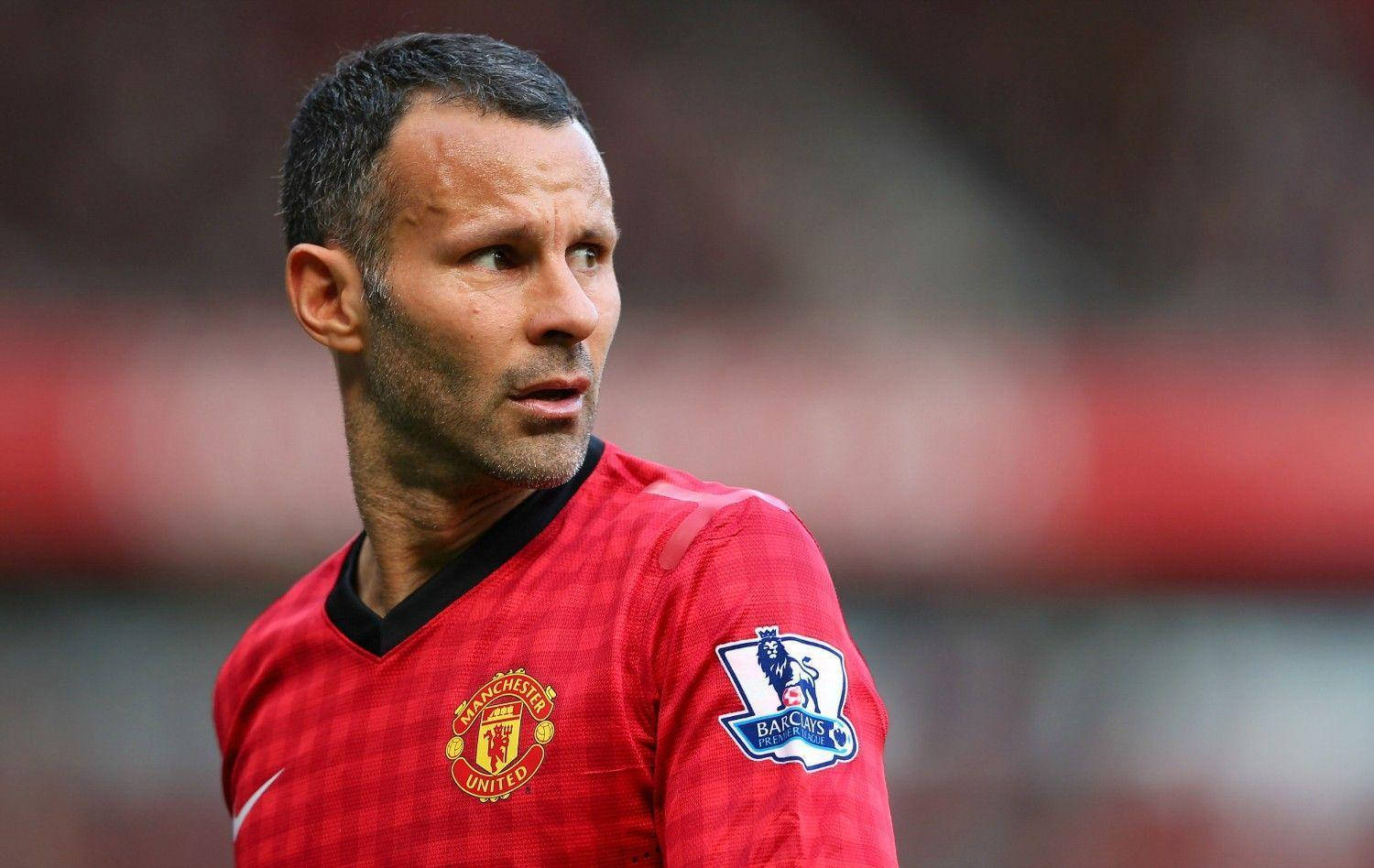 Ryan Giggs 桌布 壁紙 — 一位身穿紅色曼聯球衣的專注足球員在球場燈光下比賽時凝視著。