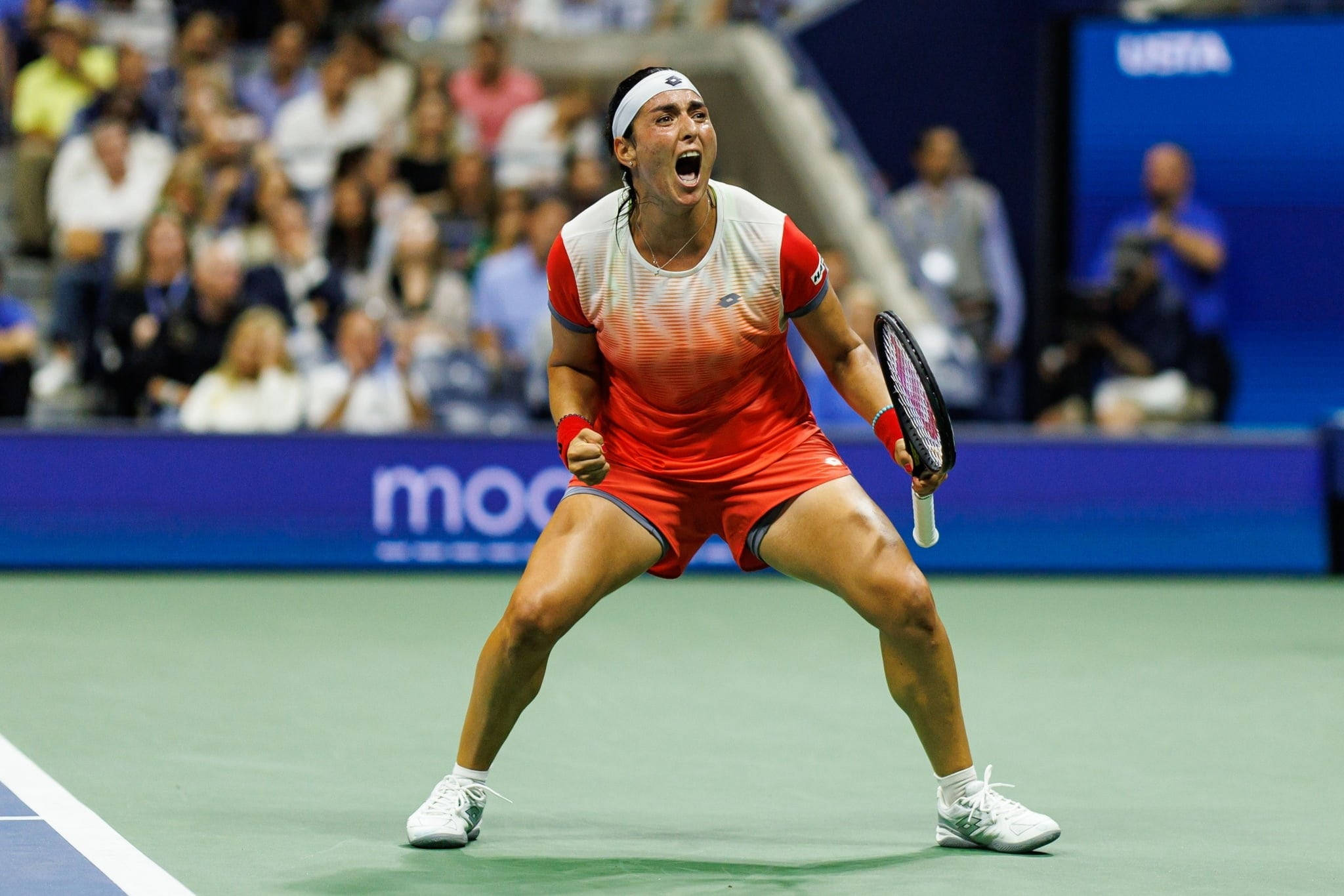 Tennis 桌布 壁紙 — 一位身穿紅色服裝的女網球選手在綠色球場上發出勝利的吼叫，背景是模糊的觀眾。