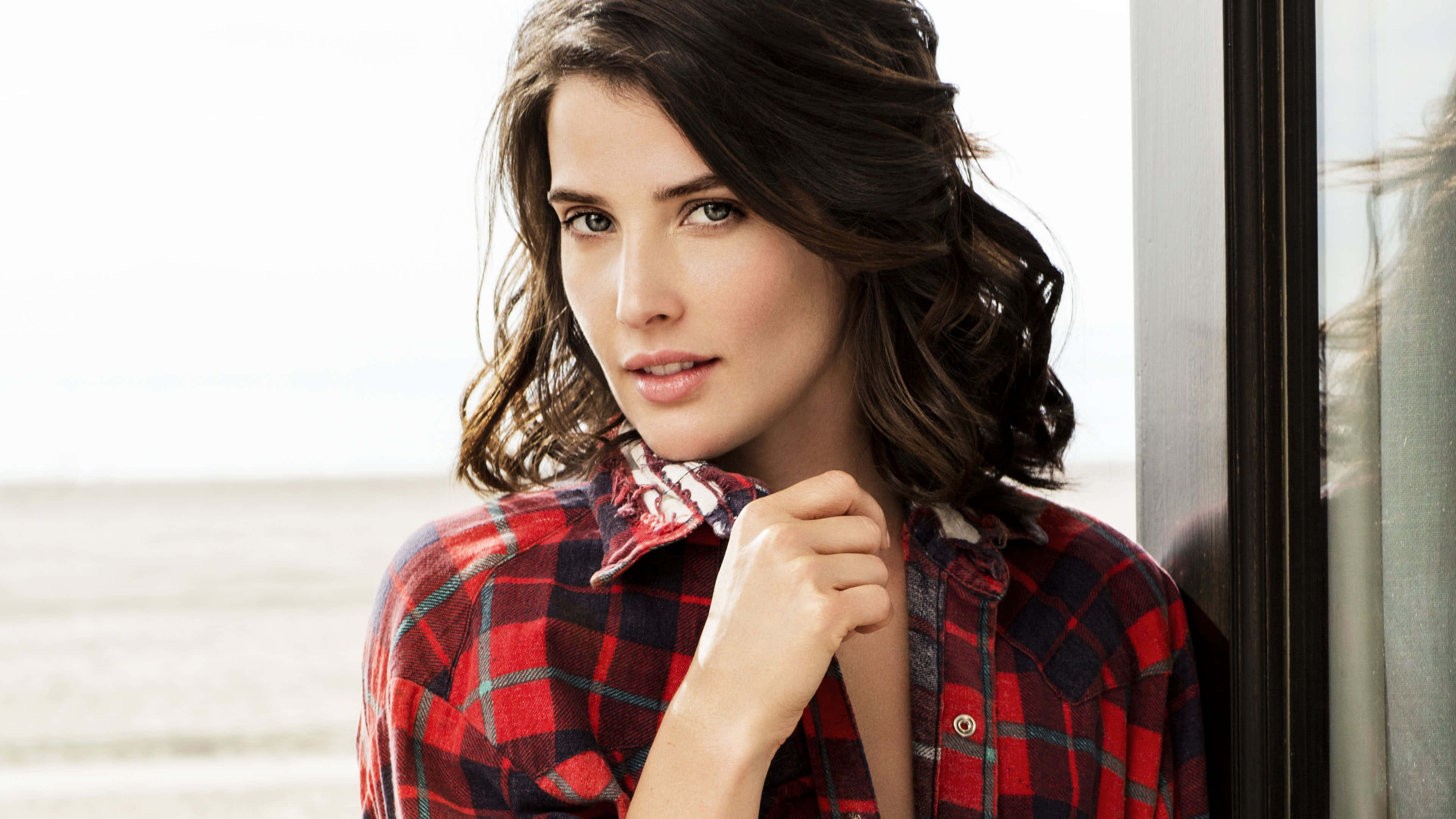 Cobie Smulders 桌布 壁紙 — 一位身穿紅色格紋襯衫的女人靠在窗邊，背景是模糊的海灘。