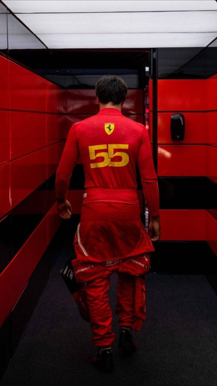 Man 桌布 壁紙 — 一位身穿紅色法拉利賽車服、號碼55的F1車手走在一條紅黑隧道中。