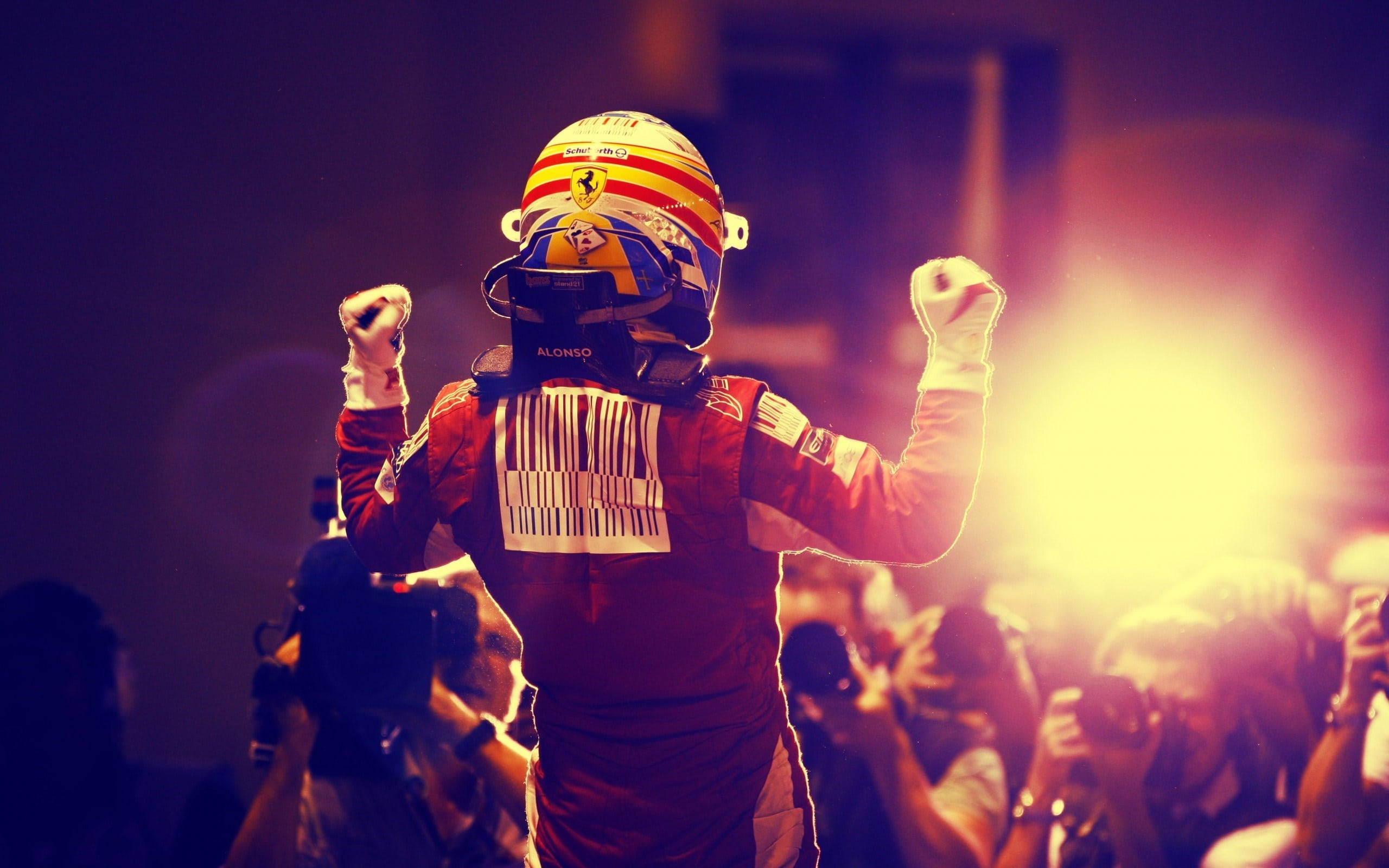 Fernando Alonso 桌布 壁紙 — 一位身穿紅色法拉利賽車服和頭盔的F1車手，在身後明亮的體育場燈光照射下，高舉拳頭慶祝。