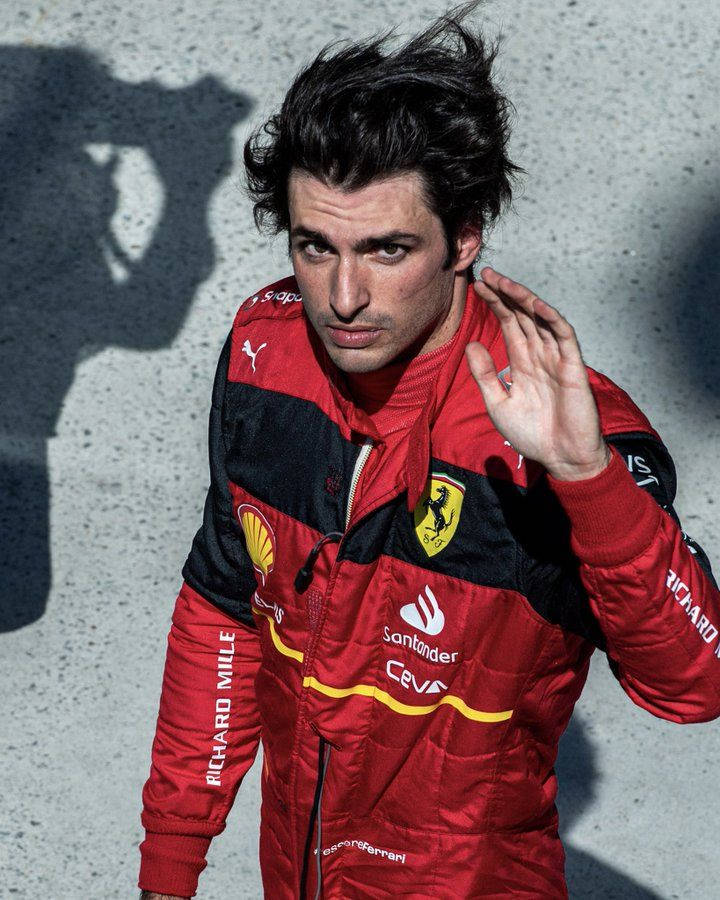 Racing 桌布 壁紙 — 一位身穿紅色法拉利賽車服的F1車手靠著混凝土牆站立，身後投射出戲劇性的陰影。