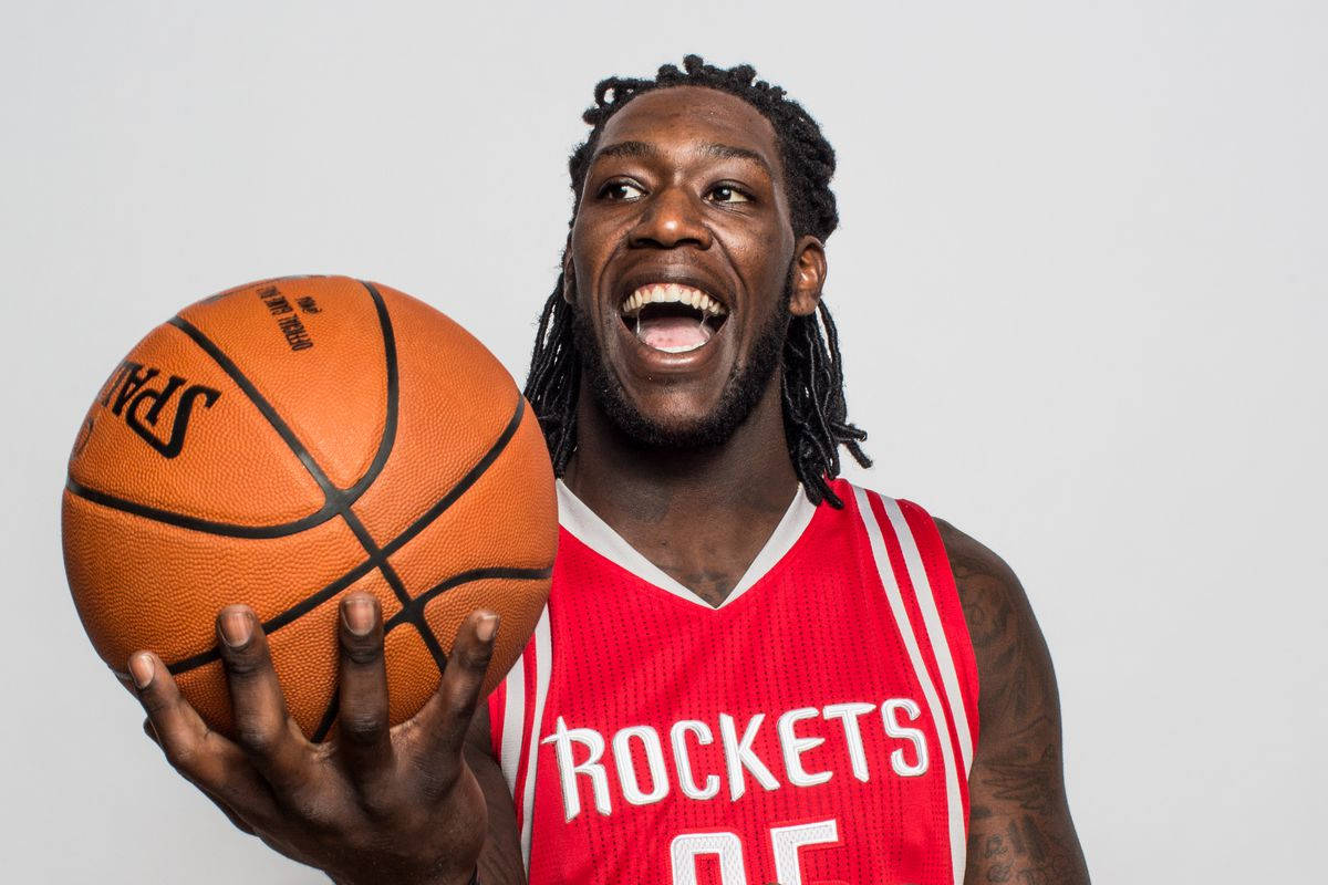 montrezl harrell 桌布 壁紙 — 一位身穿紅色火箭隊球衣的快樂籃球運動員，在純白色背景前拿著橙色Spalding籃球大笑。