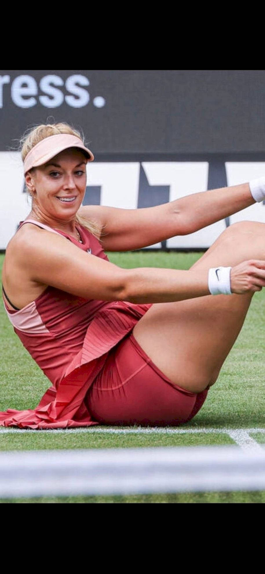 Tennis 桌布 壁紙 — 一位身穿紅色球衣、面帶微笑的女網球選手在草地場上賽後坐著伸展。