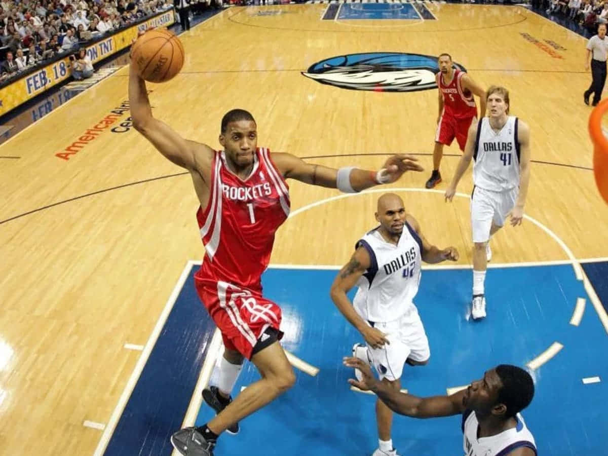 Tracy Mcgrady 桌布 壁紙 — 一位身穿紅色球衣的休士頓火箭球員跳起投籃，三名達拉斯獨行俠防守球員在激烈的NBA比賽中逼近。