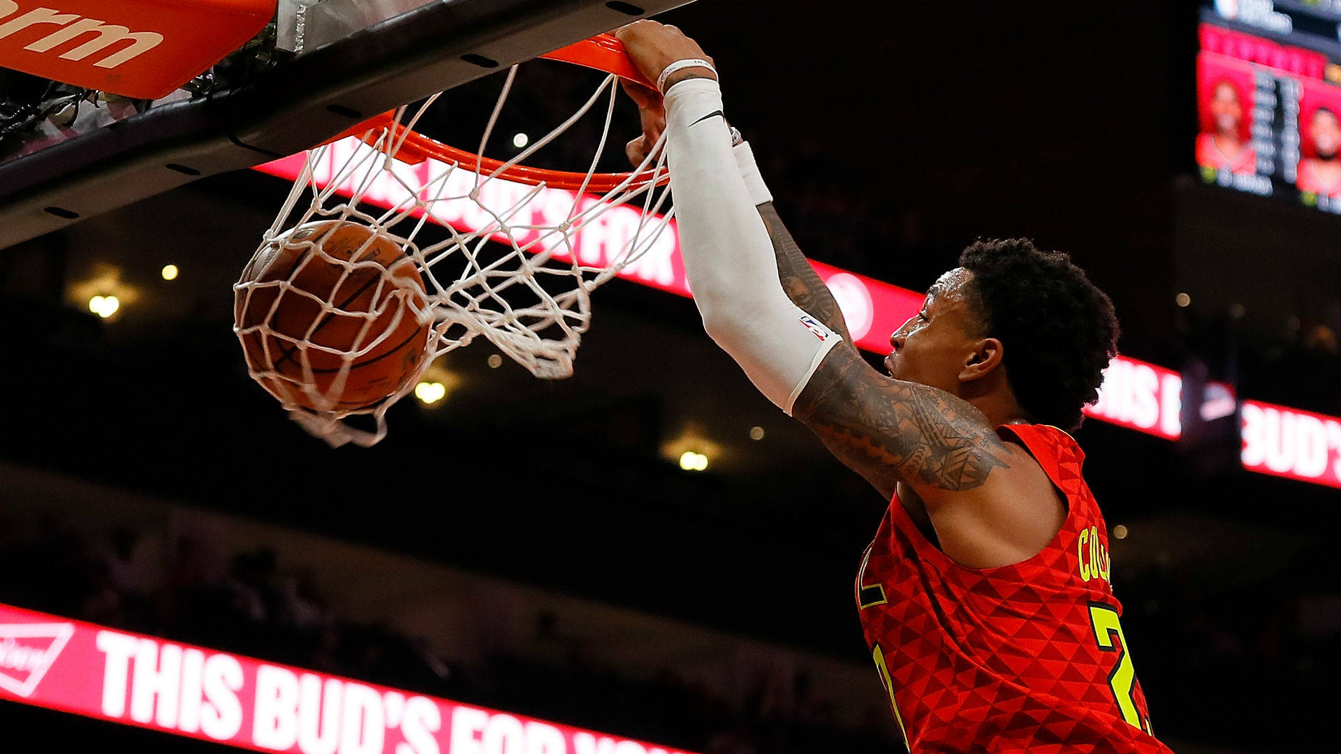 John Collins 桌布 壁紙 — 一位身穿紅色球衣的籃球運動員在明亮的場館燈光下大力灌籃。
