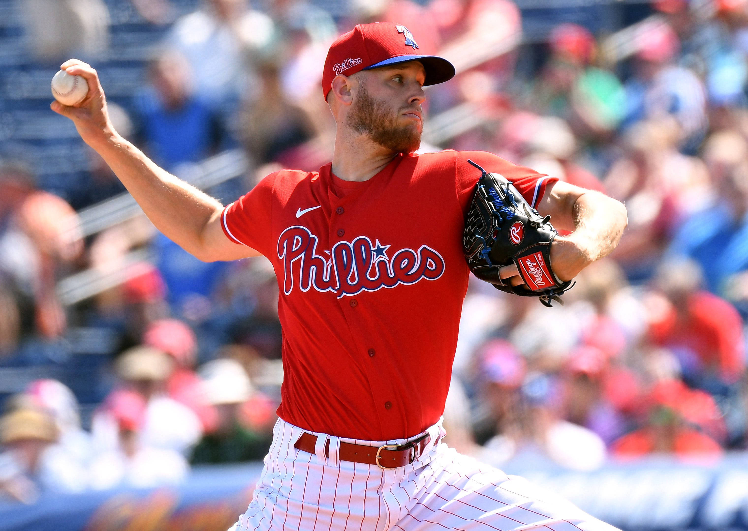Phillies 桌布 壁紙 — 一位身穿紅色球衣的費城費城人隊投手在日間比賽中揮臂投擲棒球，背景是模糊的觀眾。