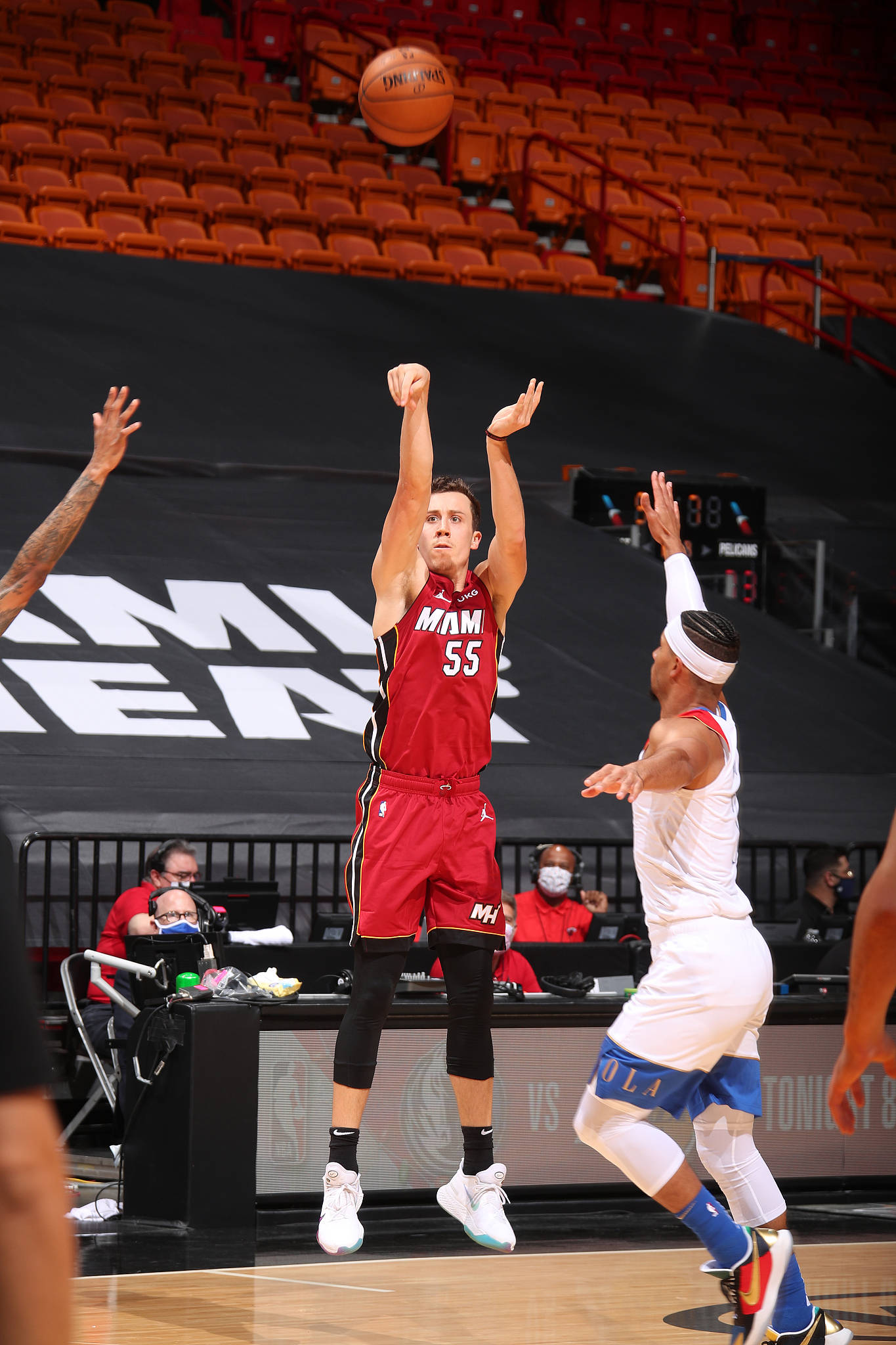 duncan robinson 桌布 壁紙 — 一位身穿紅色球衣的邁阿密熱火球員跳起投籃，而一位身穿白色球衣的防守球員在室內場館試圖封阻他。