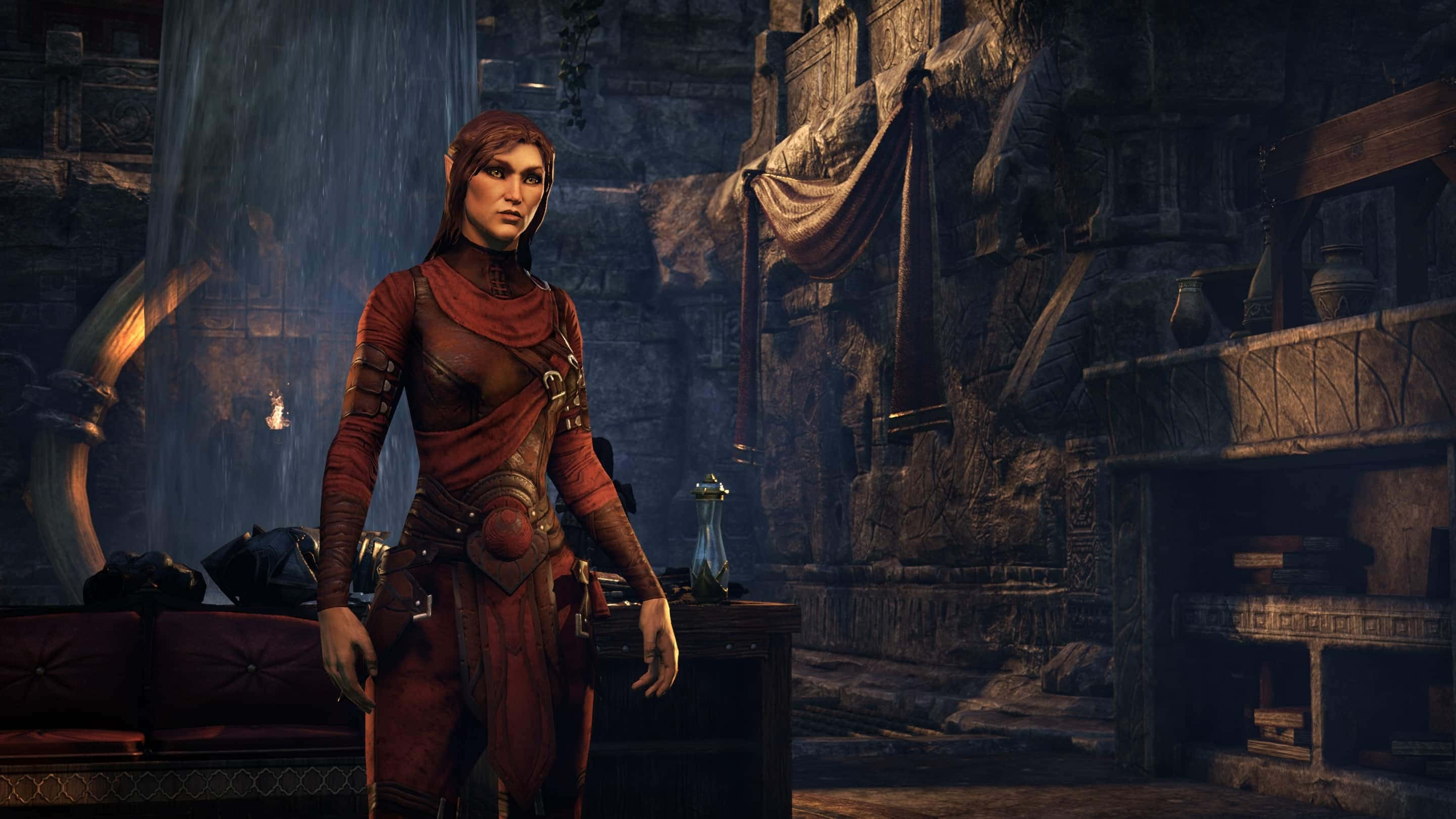 Thieves Guild 桌布 壁紙 — 一位身穿紅色盔甲的女性精靈站在光線昏暗的石頭廢墟中，周圍有懸掛的布料和古老的雕刻。