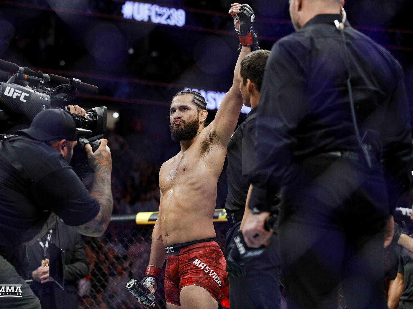Victory 桌布 壁紙 — 一位身穿紅色短褲的UFC勝利拳手，在裁判於八角籠內宣布他為勝者時，舉起戴著手套的拳頭。