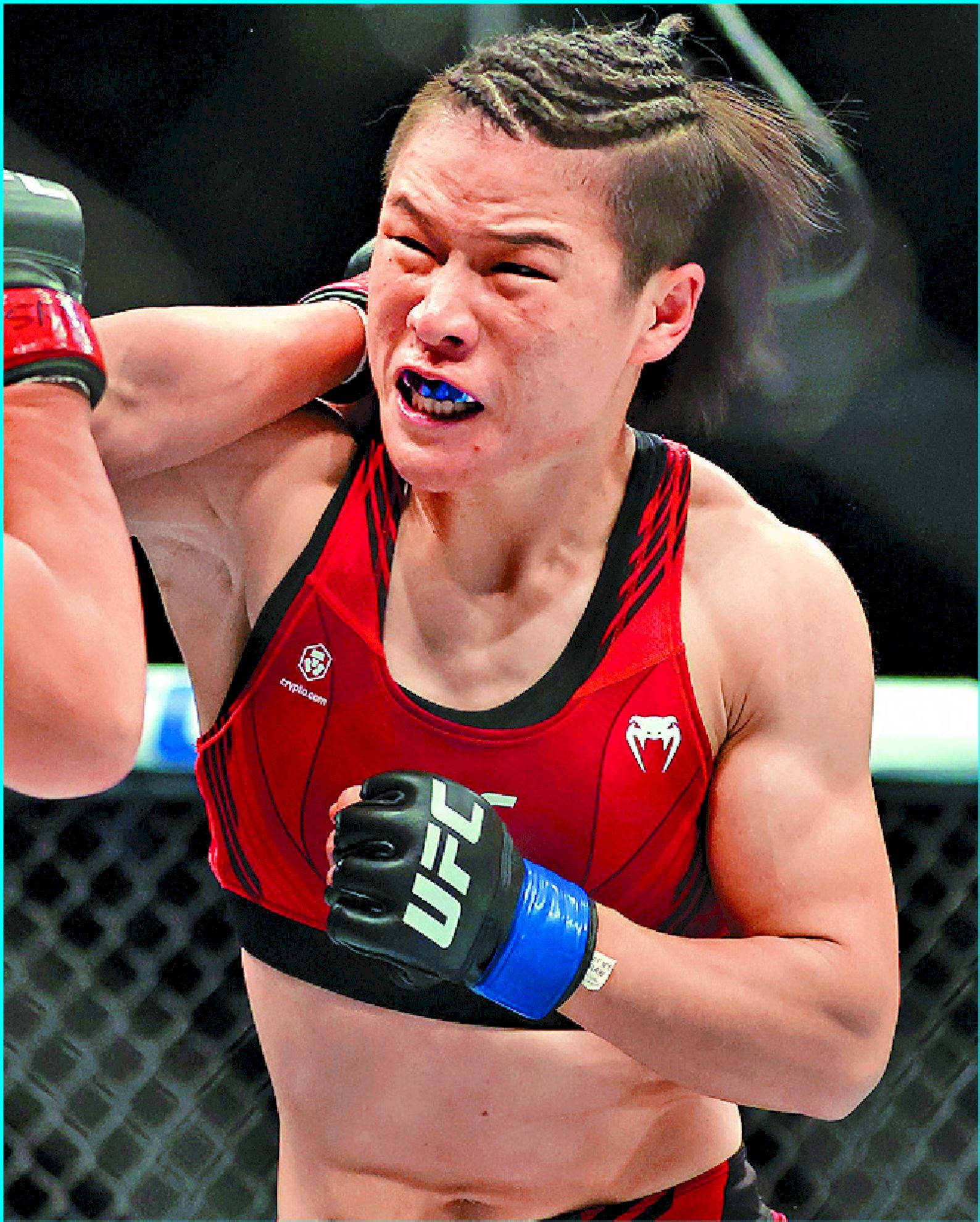 Athletic 桌布 壁紙 — 一位身穿紅色裝備的女性MMA拳手在八角籠內比賽中痛苦地扭曲表情。
