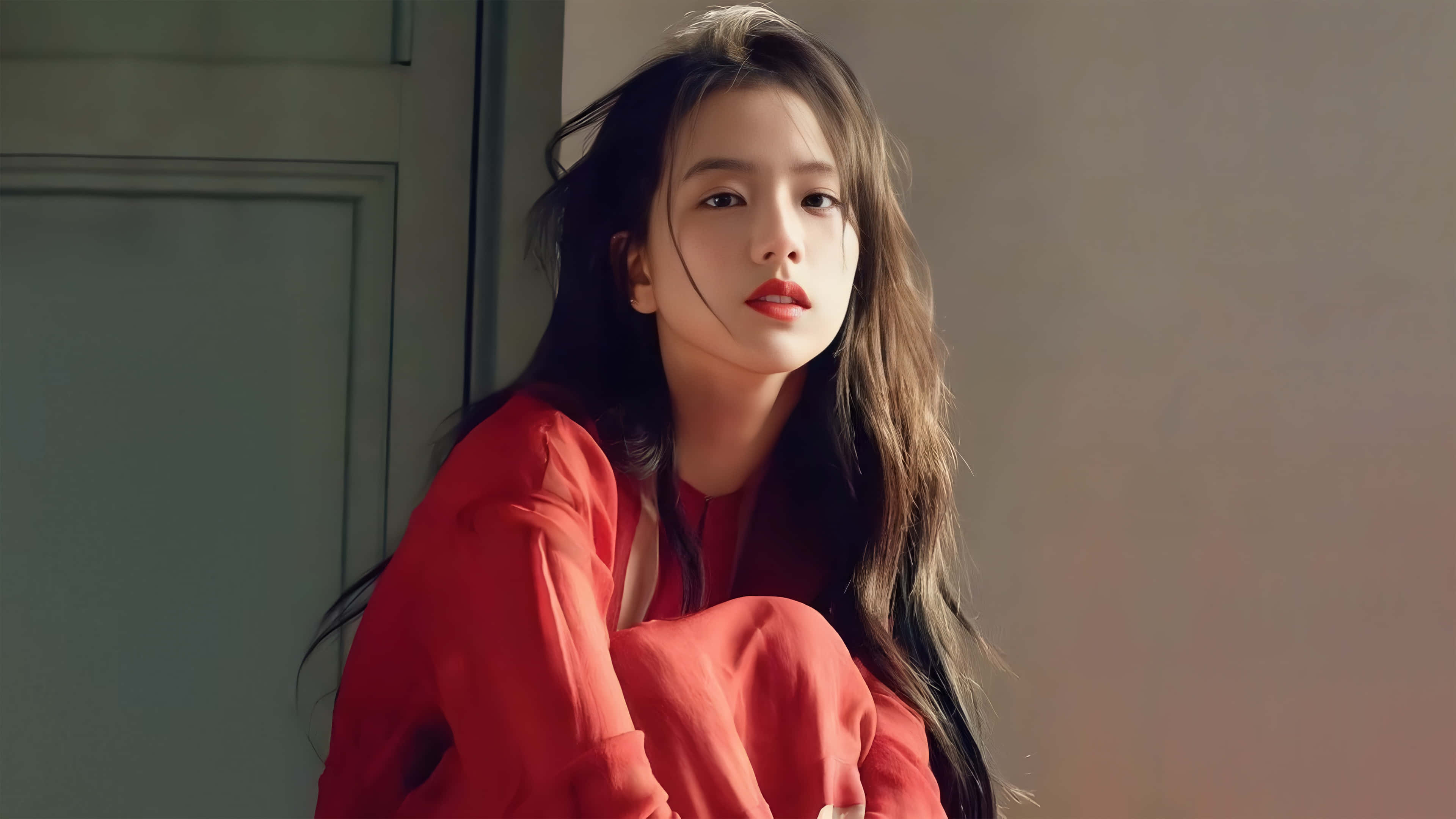 BLACKPINK 桌布 壁紙 — 一位身穿紅色襯衫的年輕女子倚在門框上，沐浴在柔和自然光中。