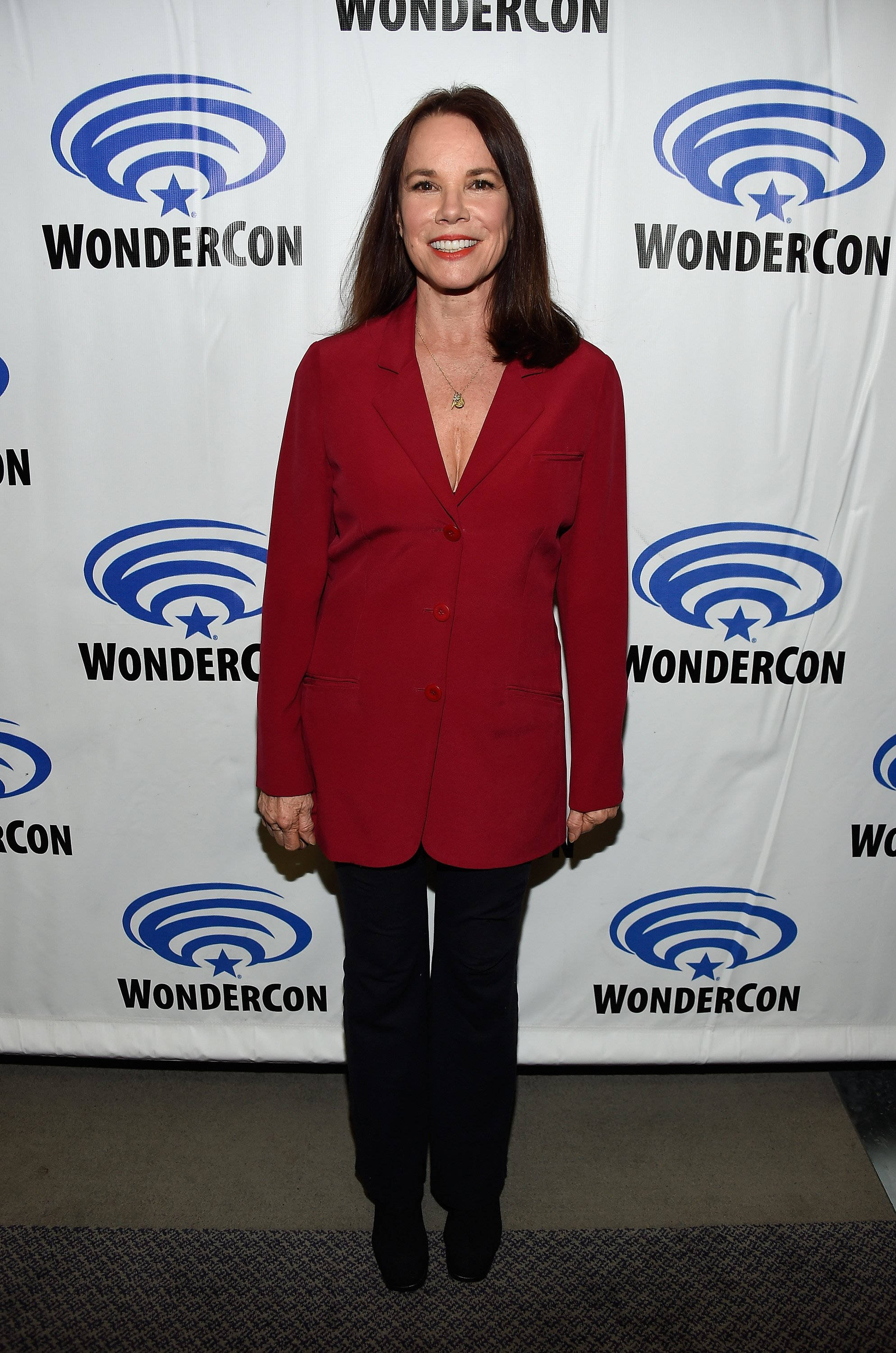 Celebrity 桌布 壁紙 — 一位身穿紅色西裝外套的女性在WonderCon品牌背景前對著鏡頭微笑。