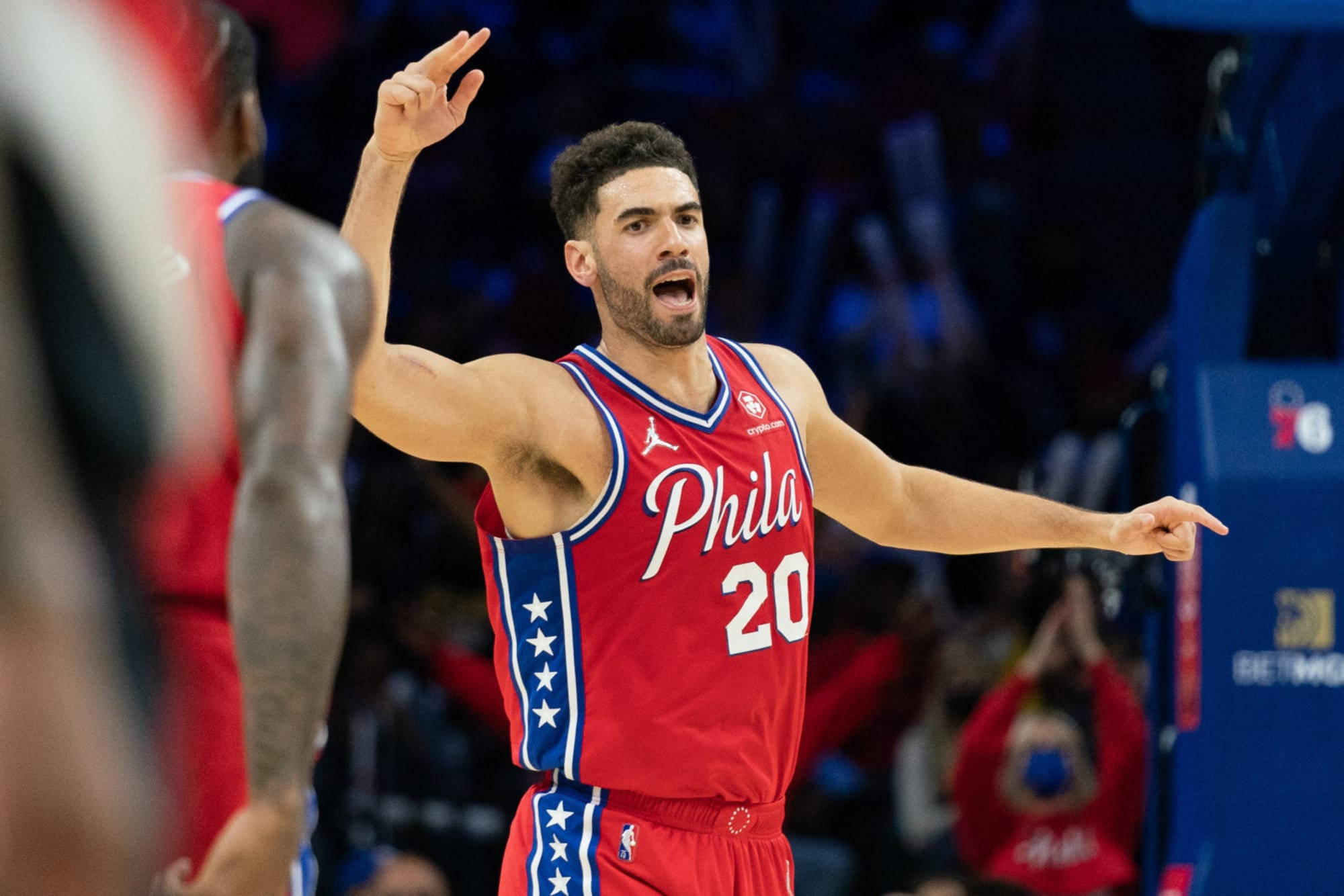 76ers 桌布 壁紙 — 一位身穿紅色費城球衣、背號20的籃球運動員在比賽中張開雙臂熱情慶祝。