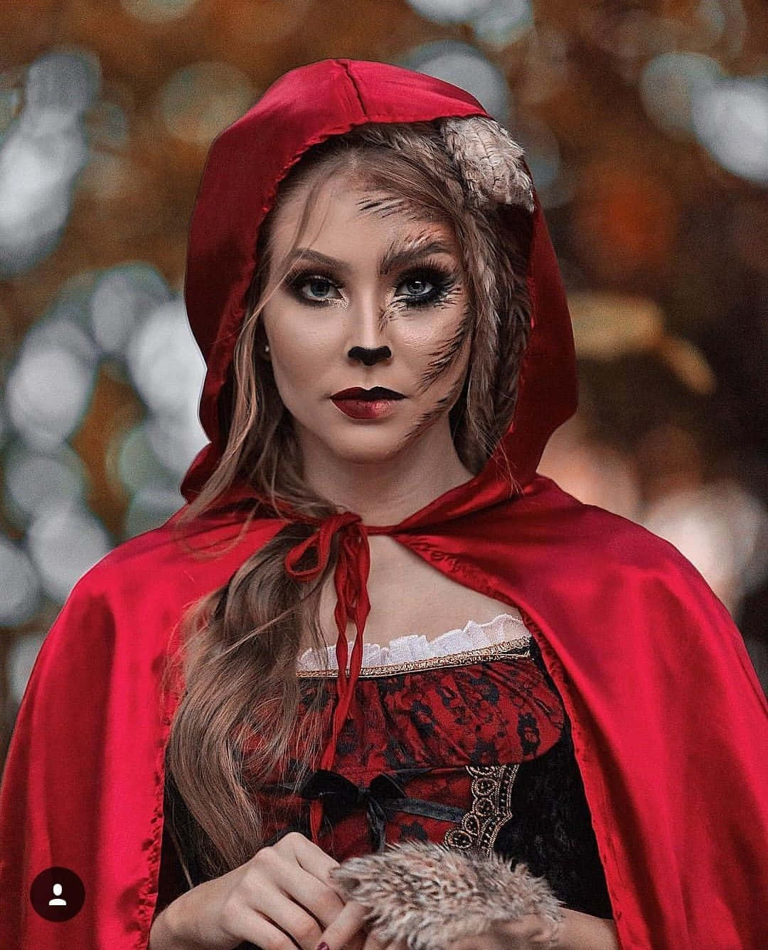 Halloween Costume 桌布 壁紙 — 一位身穿紅色連帽斗篷、化著狼妝的女子，在模糊的秋日背景下凝視著。