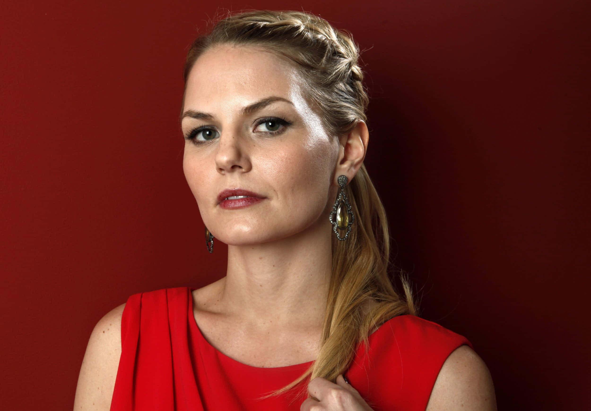 jennifer morrison 桌布 壁紙 — 一位身穿紅色連衣裙、辮子頭髮的女性在深紅色背景下直視鏡頭。