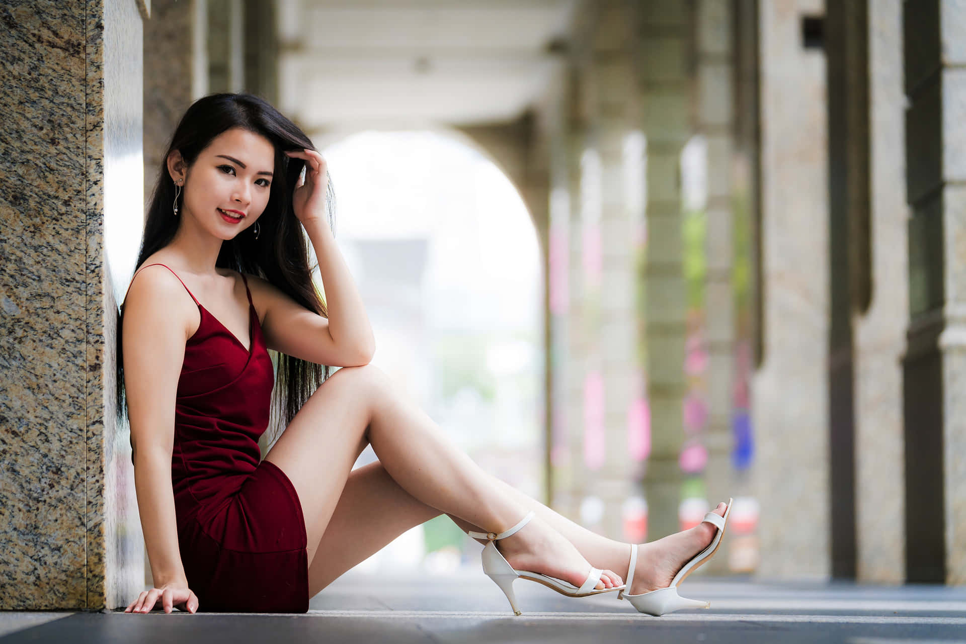 身穿紅色連衣裙和白色高跟鞋的女性靠在拱廊的石柱上。 — 漂亮的動圖 壁紙