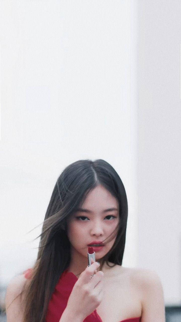 Jennie 桌布 壁紙 — 一位身穿紅色連衣裙的女性在純白背景下，頭髮隨風飄揚，塗抹紅色唇膏。