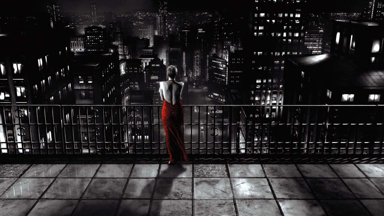 Film Noir 桌布 壁紙 — 一位身穿紅色連衣裙的女性獨自站在屋頂陽台上，俯瞰著夜晚廣闊的城市景觀。