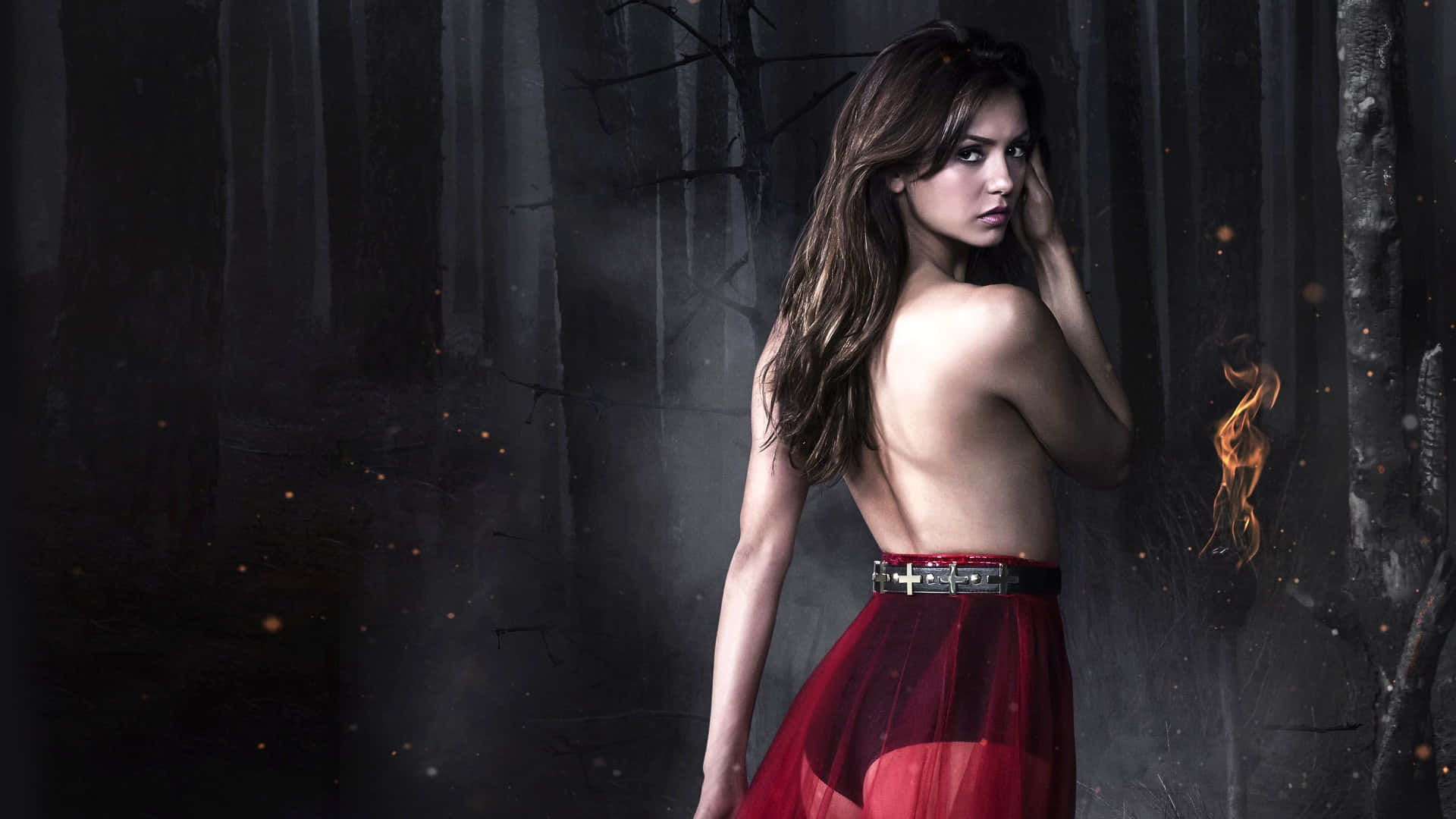 Vampire Diaries Desktop 桌布 壁紙 — 一位身穿紅色連衣裙的女性站在黑暗的森林中，周圍有螢火蟲，手邊有一小簇火焰。