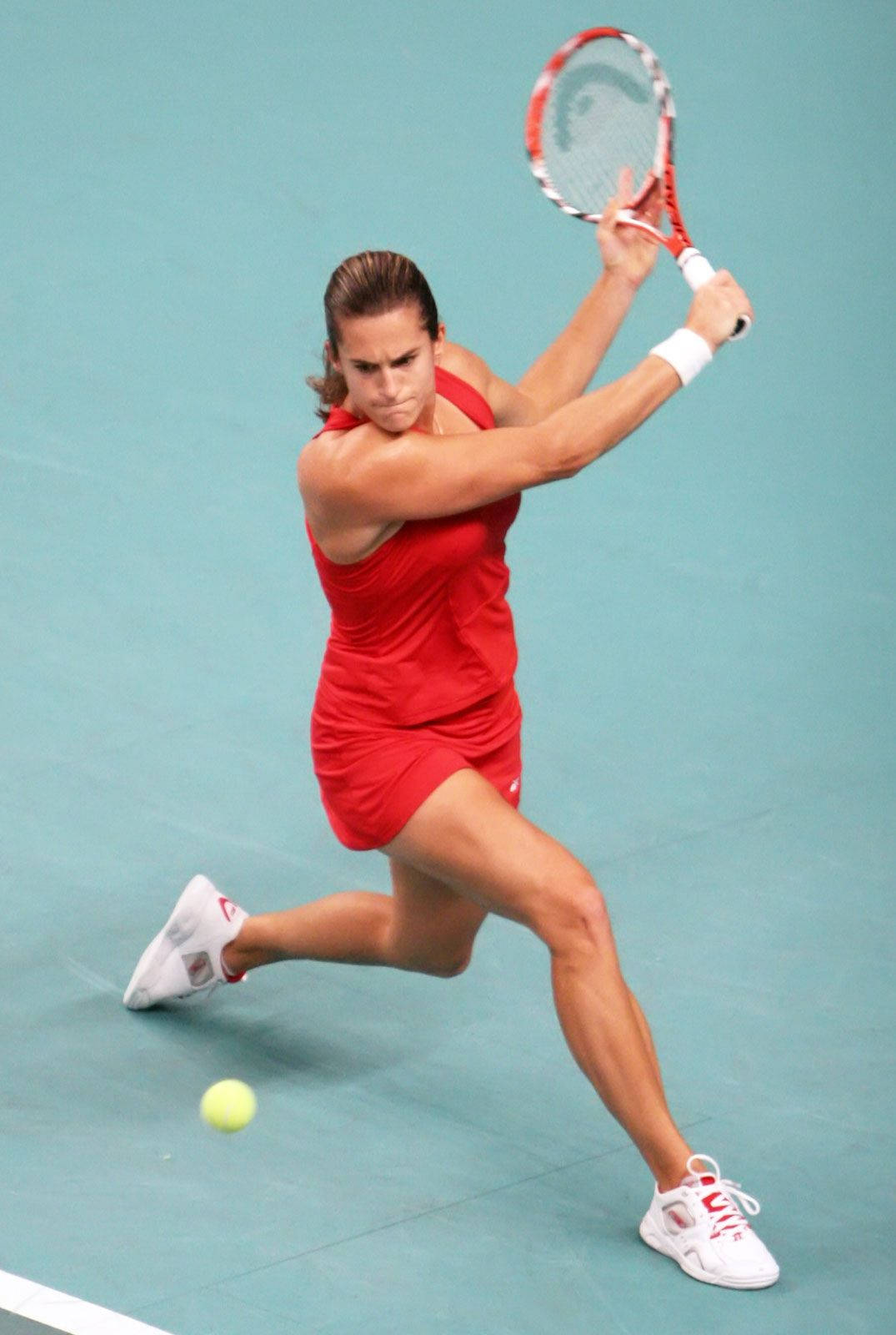 Athletic 桌布 壁紙 — 一位身穿紅色連衣裙的女網球運動員在青綠色球場上揮拍擊打黃色球。