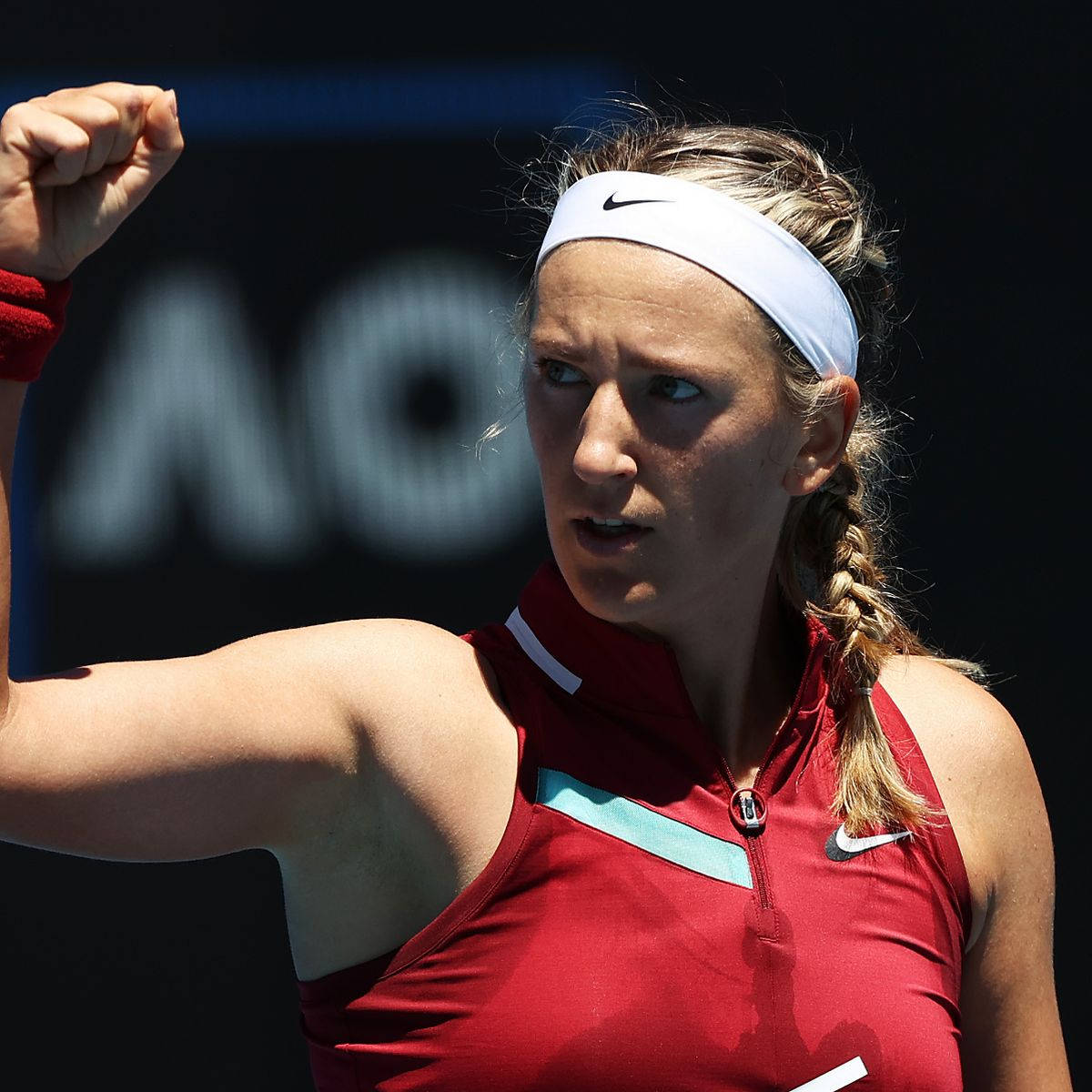 Athletic 桌布 壁紙 — 一位身穿紅色運動服的堅定女網球選手在明媚陽光下高舉拳頭慶祝勝利。
