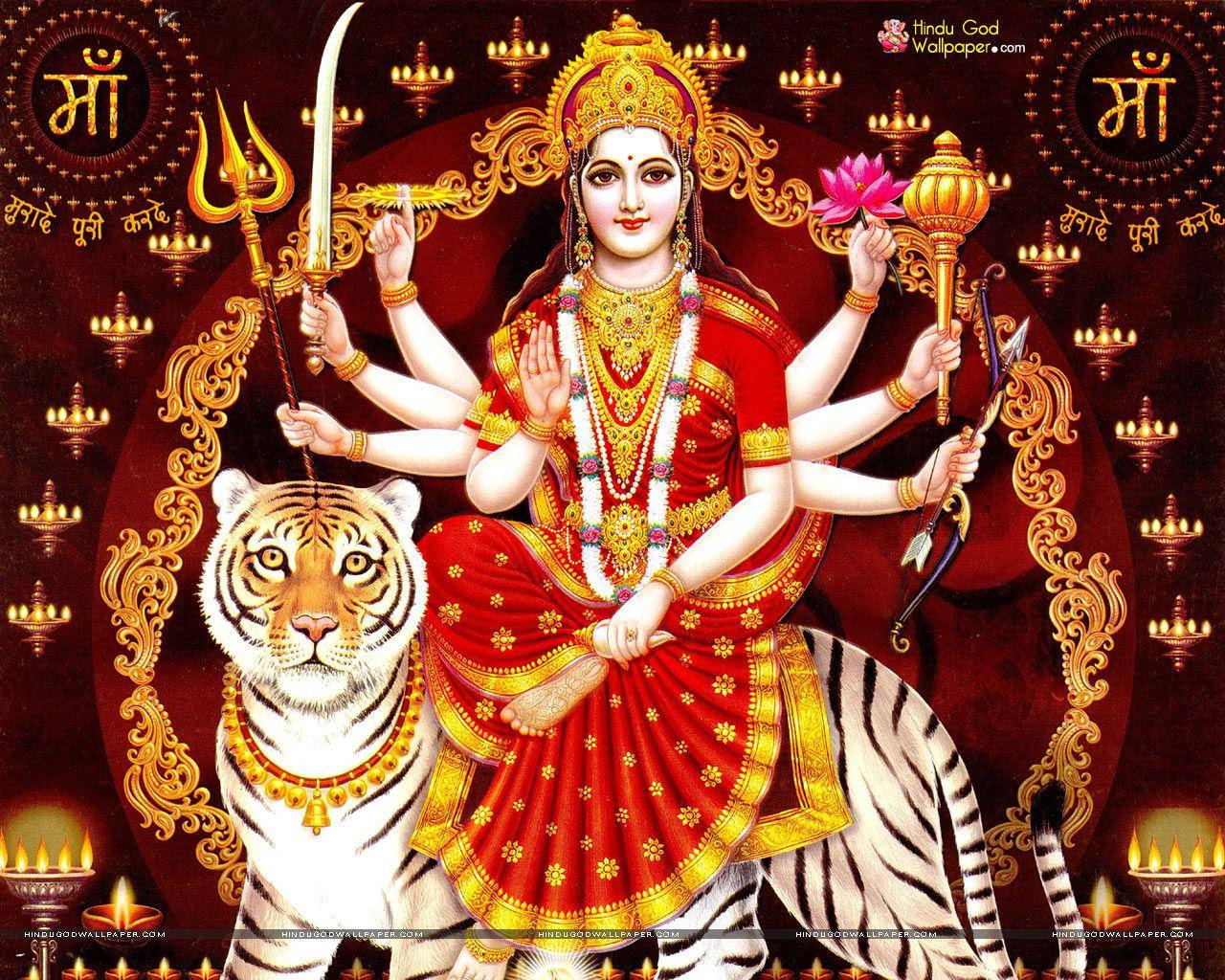 Vaishno Devi 桌布 壁紙 — 一位身穿紅金服飾、光芒四射的多臂印度教女神坐在雄偉的老虎上，周圍環繞著發光的燈籠。