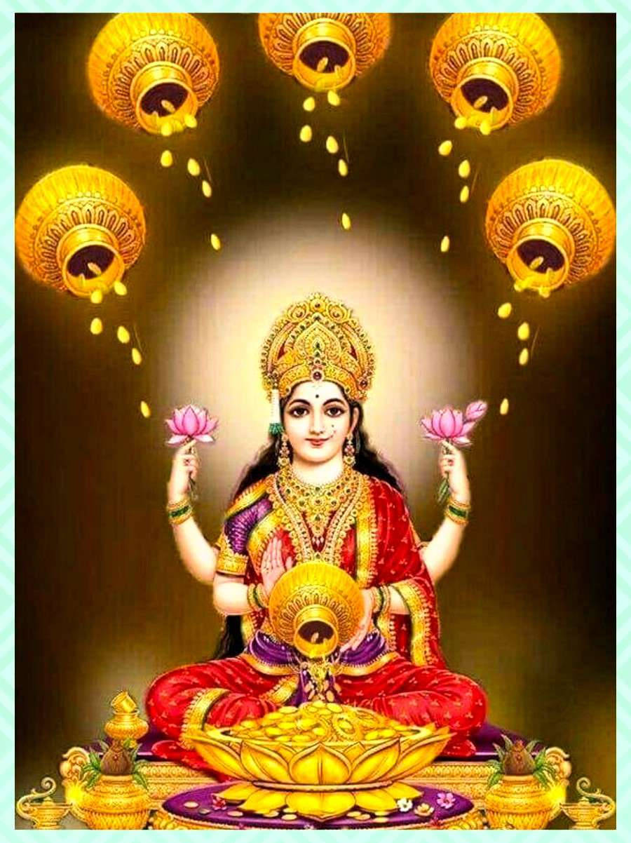 Lakshmi Devi 桌布 壁紙 — 一位身穿紅金服飾的神聖女神，手持粉紅蓮花，靜坐於此，上方金色燈盞傾倒著發光的油。