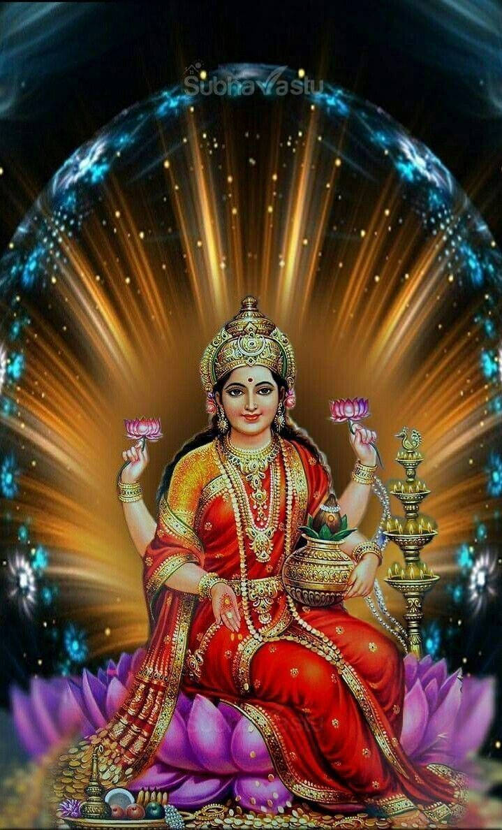 Indian 桌布 壁紙 — 一位身穿紅金色的光芒女神優雅地坐在紫色蓮花上，手持粉紅蓮花，周圍環繞著閃耀的金色和藍色光線。