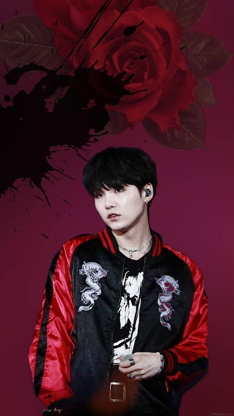 슈가 BTS 桌布 壁紙 — 一位身穿紅黑 bomber 外套的年輕男子，站在深酒紅色背景前，背景有一朵大紅玫瑰和墨水飛濺。