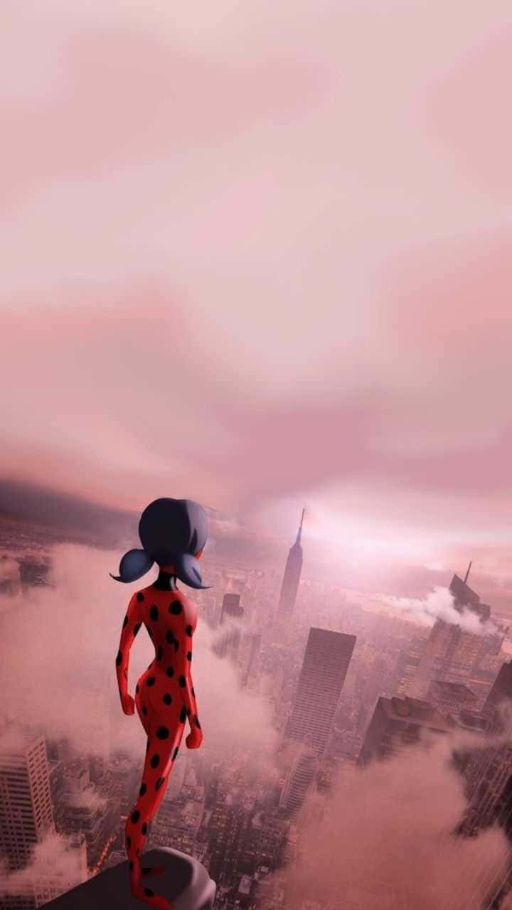 Marinette 桌布 壁紙 — 一位身穿紅黑圓點套裝的女超級英雄站在摩天大樓頂端，俯瞰著籠罩在薄霧中的粉紅色城市景觀。