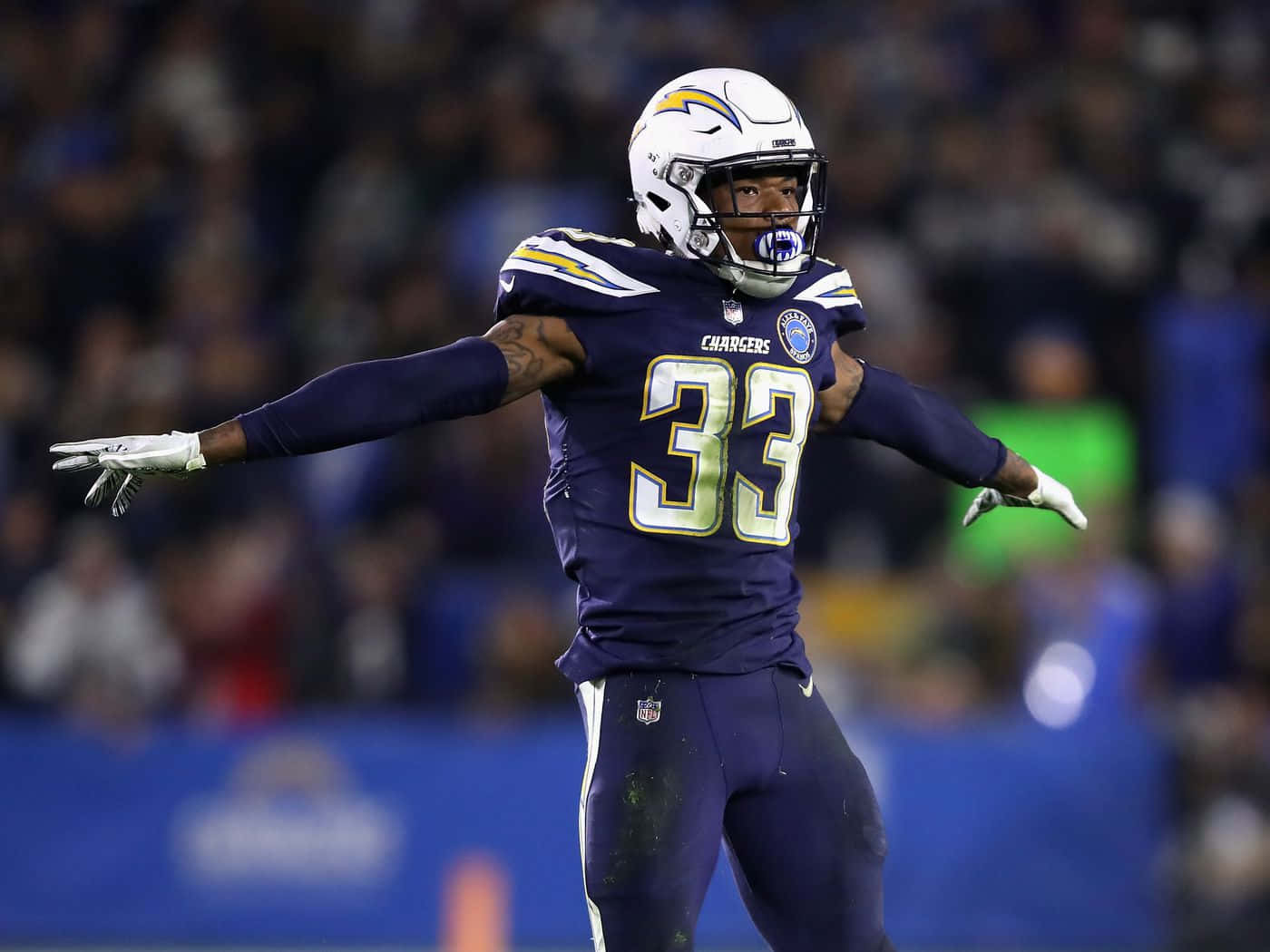 NFL 桌布 壁紙 — 一位身穿紫色33號球衣的Chargers美式足球員在球場燈光下張開雙臂慶祝。
