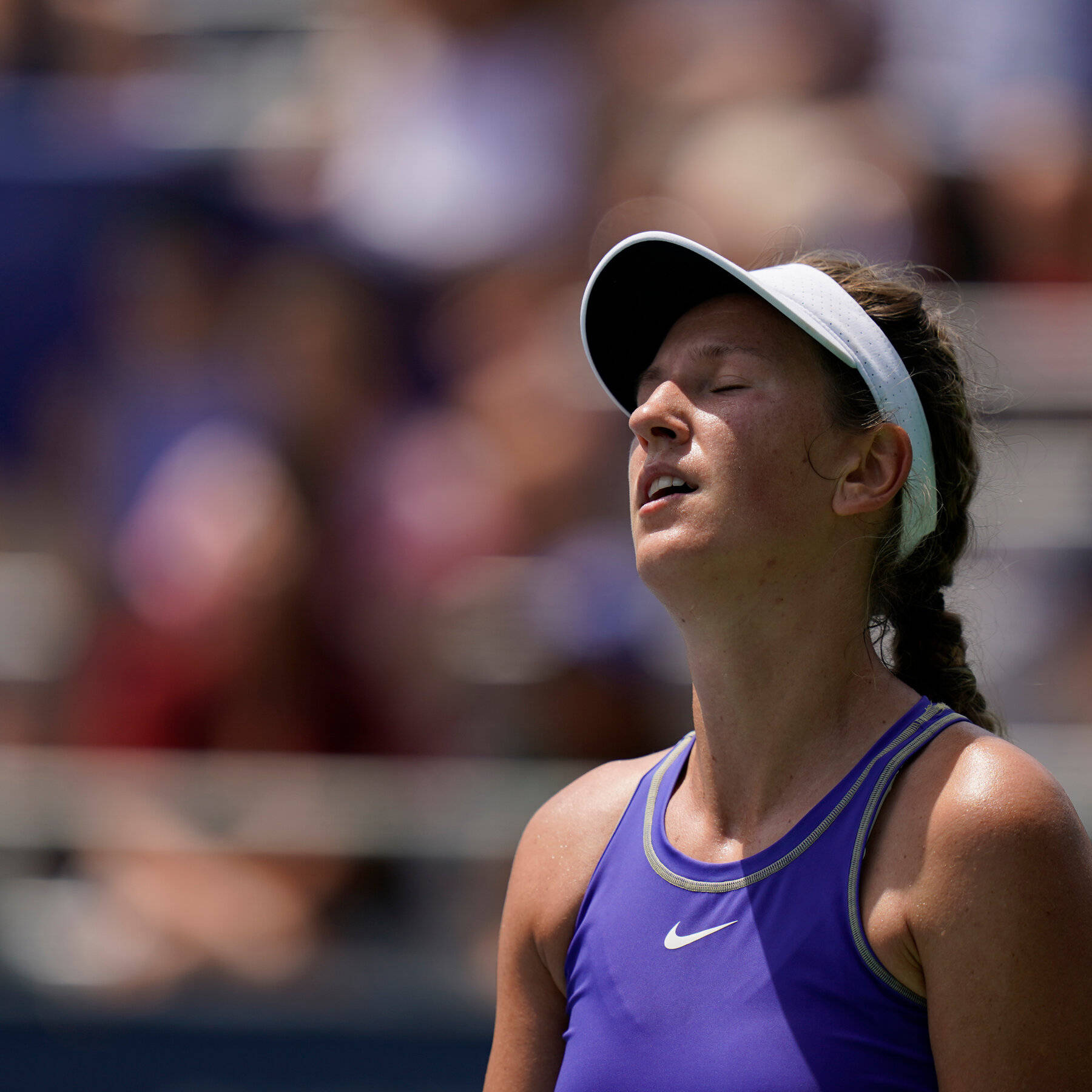 Athletic 桌布 壁紙 — 一位身穿紫色Nike背心及白色遮陽帽的女網球選手在球場上閉著眼睛，在明亮的陽光下呼氣。