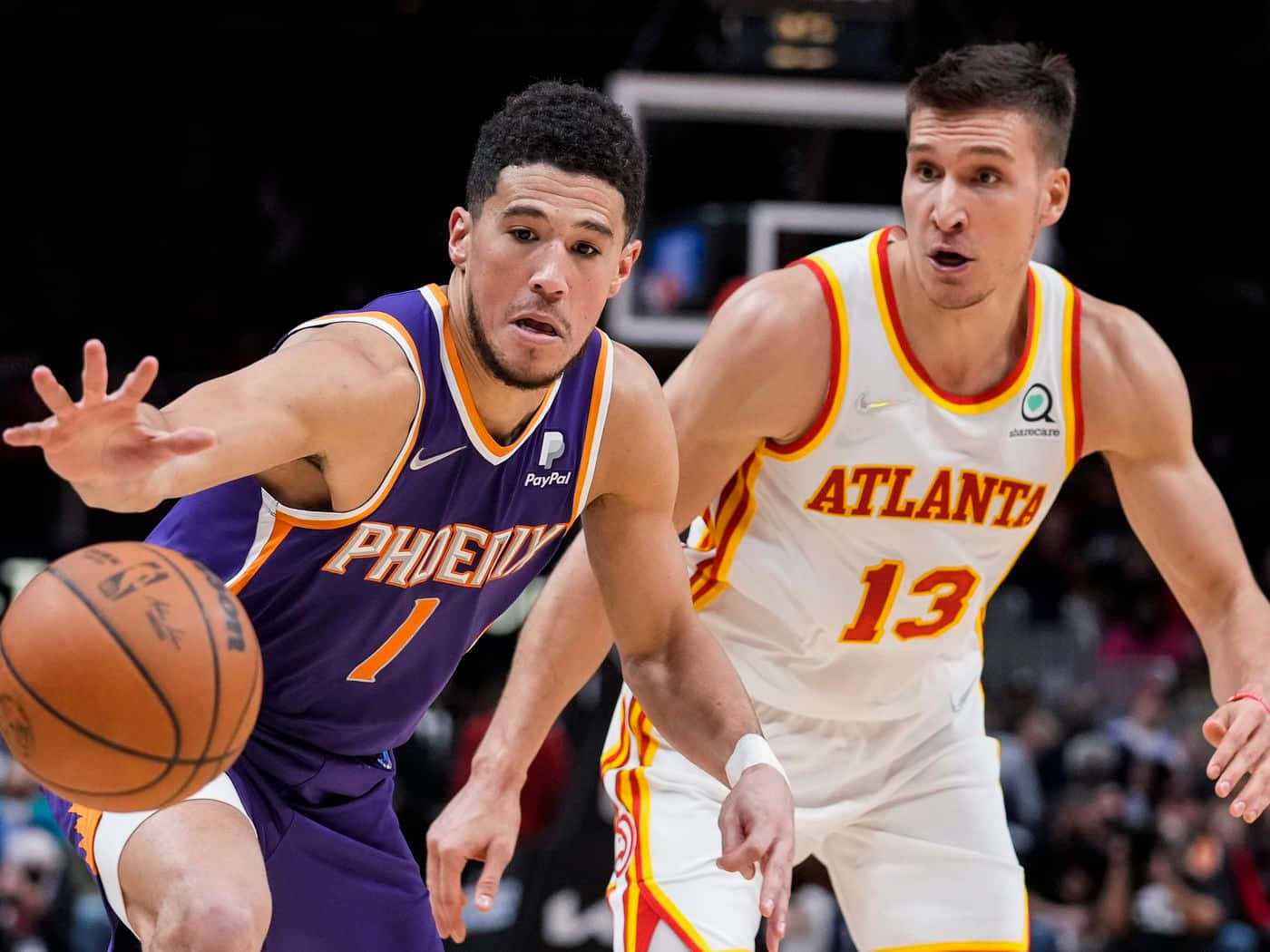 NBA 桌布 壁紙 — 一位身穿紫色的鳳凰城太陽隊球員正在運球，而一位身穿白色的亞特蘭大老鷹隊防守球員在籃球比賽中緊密防守他。