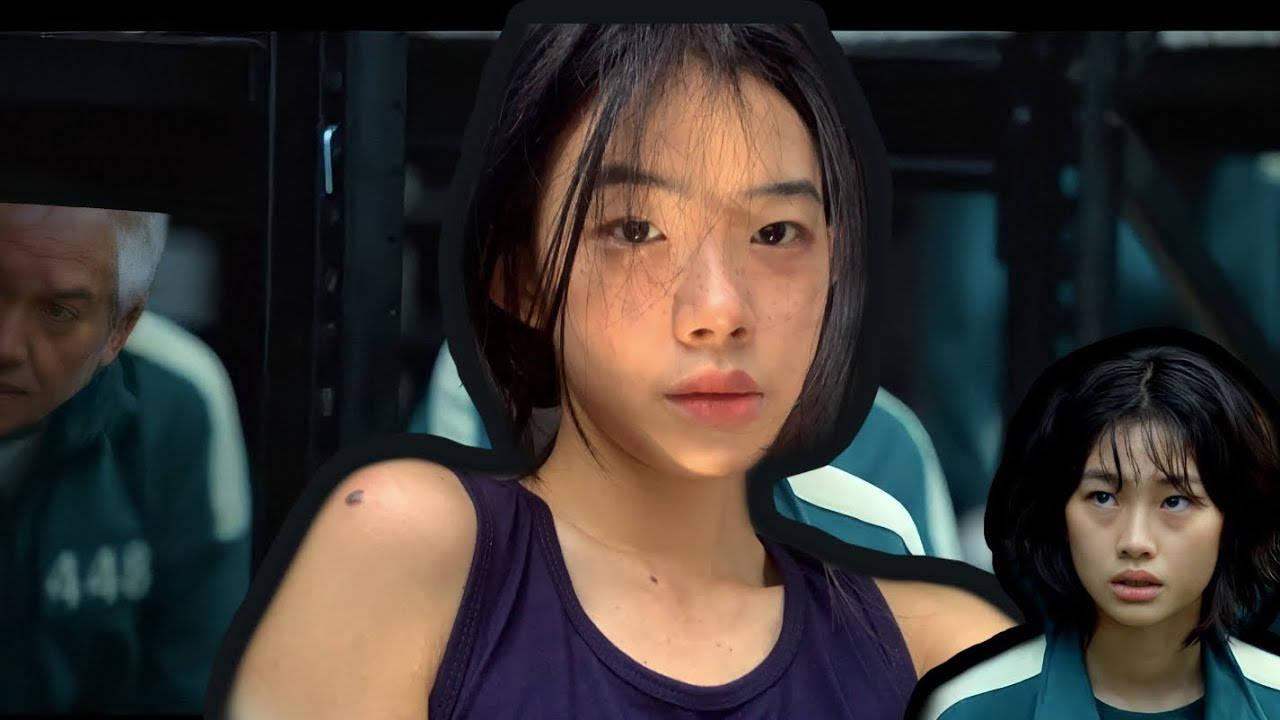 桌布 壁紙 — 一位身穿紫色背心的年輕女性，戴著黑色連帽，表情嚴肅地直視前方，在昏暗的工業環境中被另外兩個人夾在中間。
