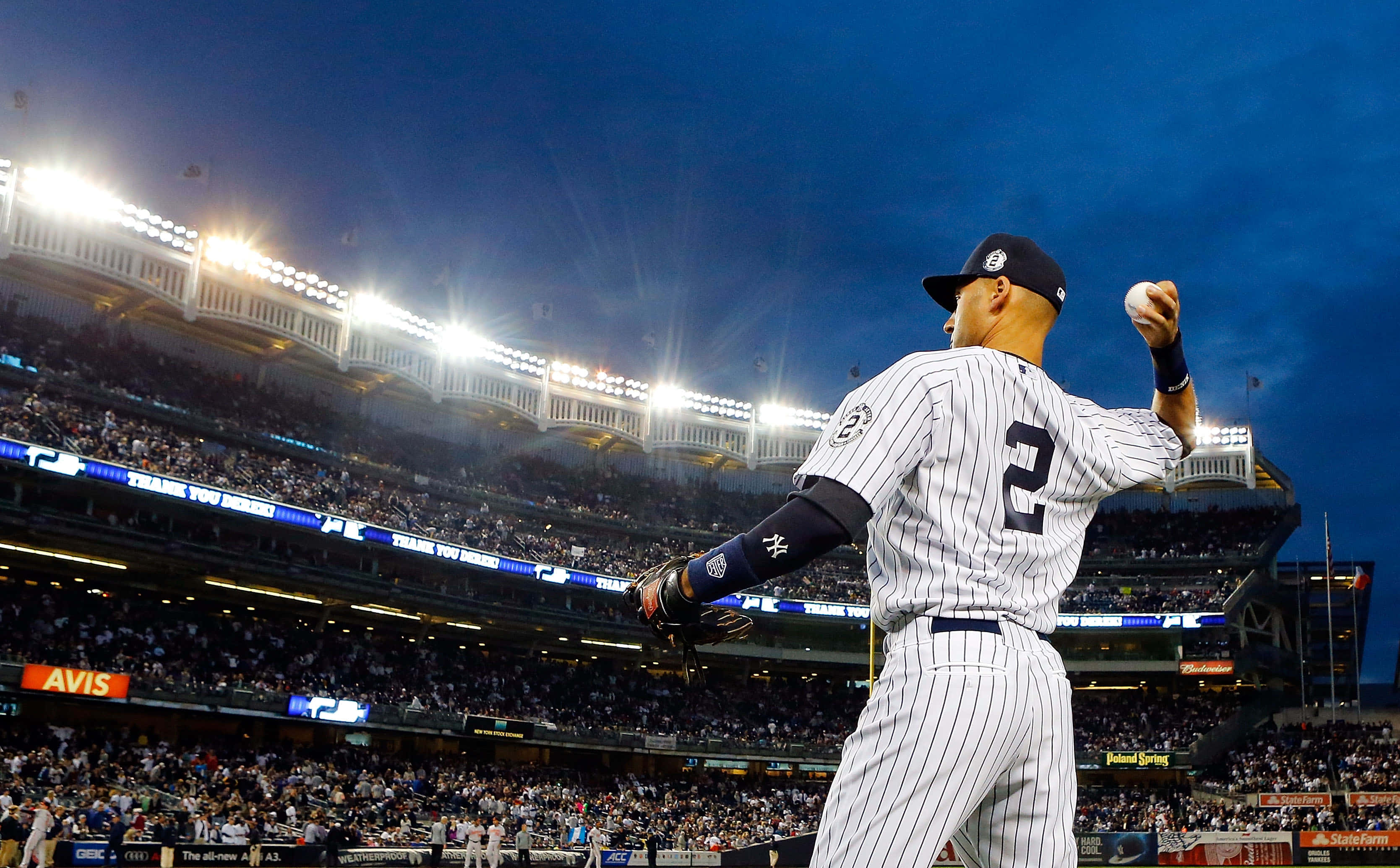 Yankees Logo 桌布 壁紙 — 一位身穿細條紋球衣的棒球投手在球場燈光下，對著暮色天空準備投球。